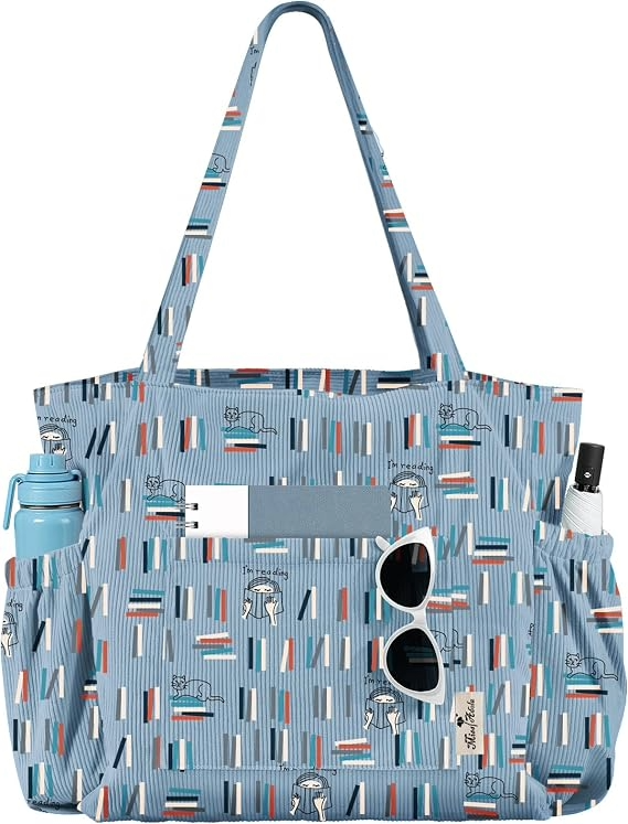 Blue book patterned tote bag with long handles, exterior pockets, water bottle and sunglasses attached, shown against a white background; practical, playful style.