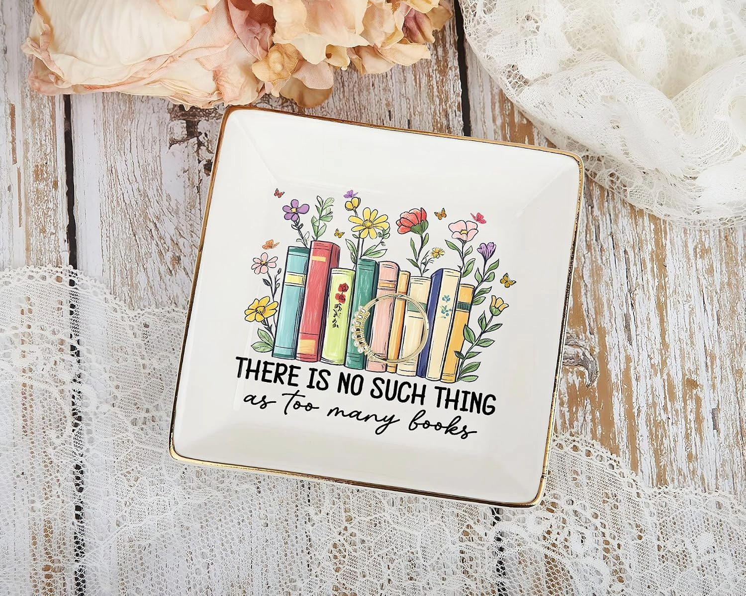 Bookish jewelry dish on rustic wood and lace, showing colorful books with flowers and the phrase “There is no such thing as too many books.”