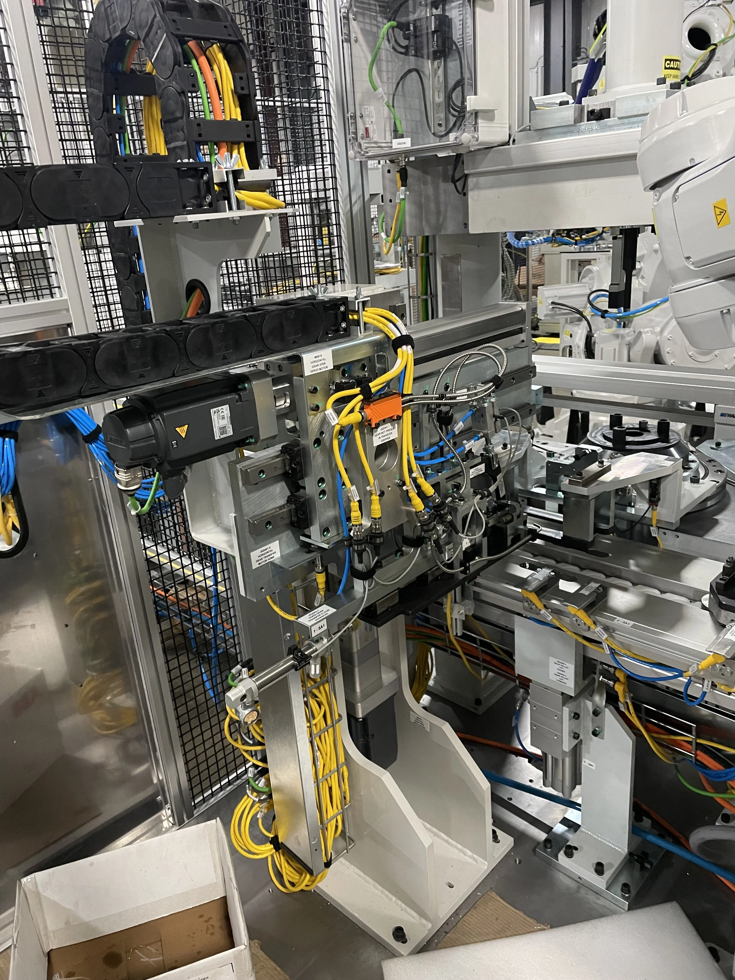Close-up of electrical wiring and components inside an industrial machine or electrical cabinet with black, yellow, and green cables, and various mechanical parts.