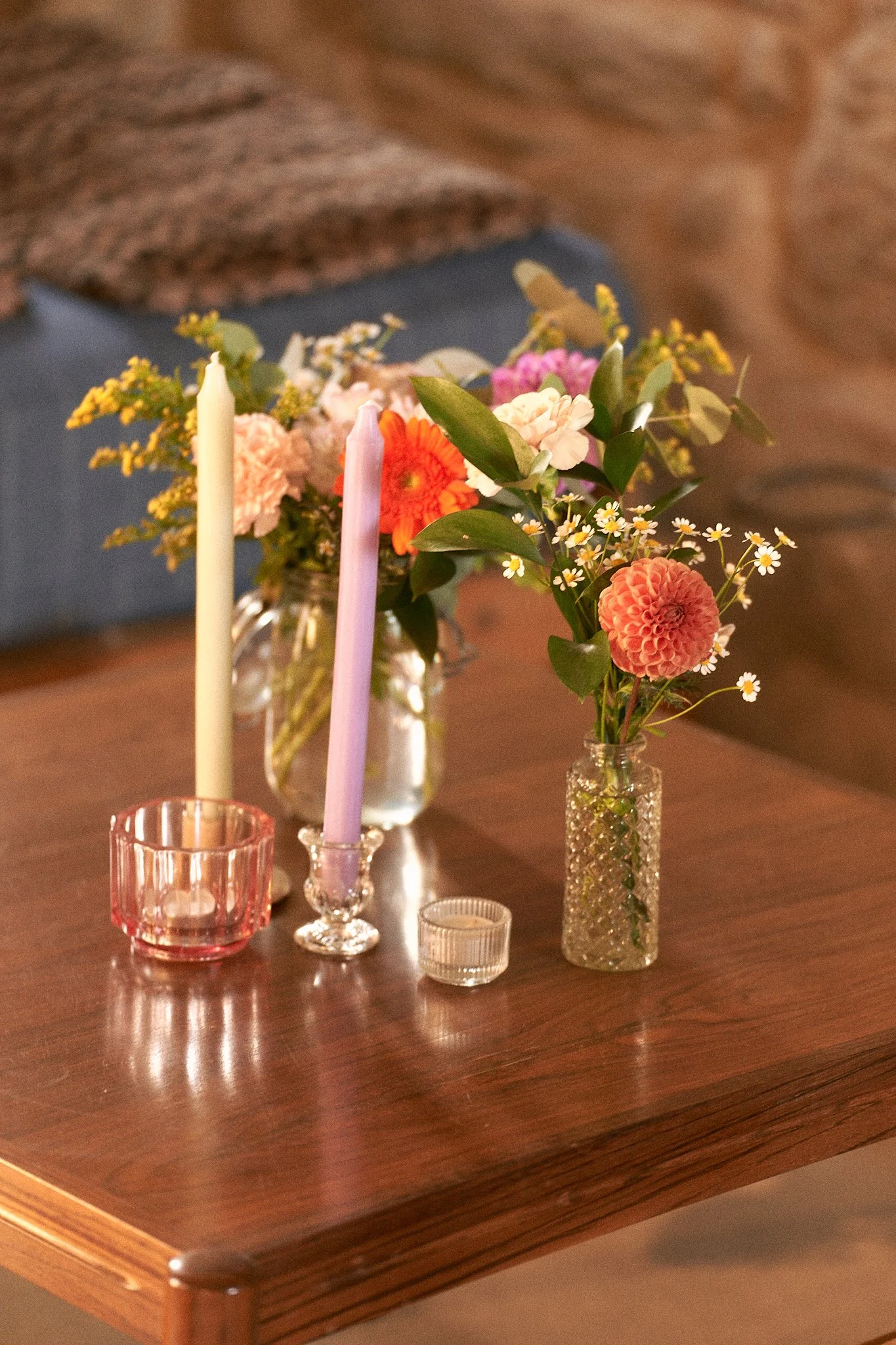 Un arrangement floral sur une table en bois avec plusieurs vases contenant des fleurs colorées et des bougies. background flou.