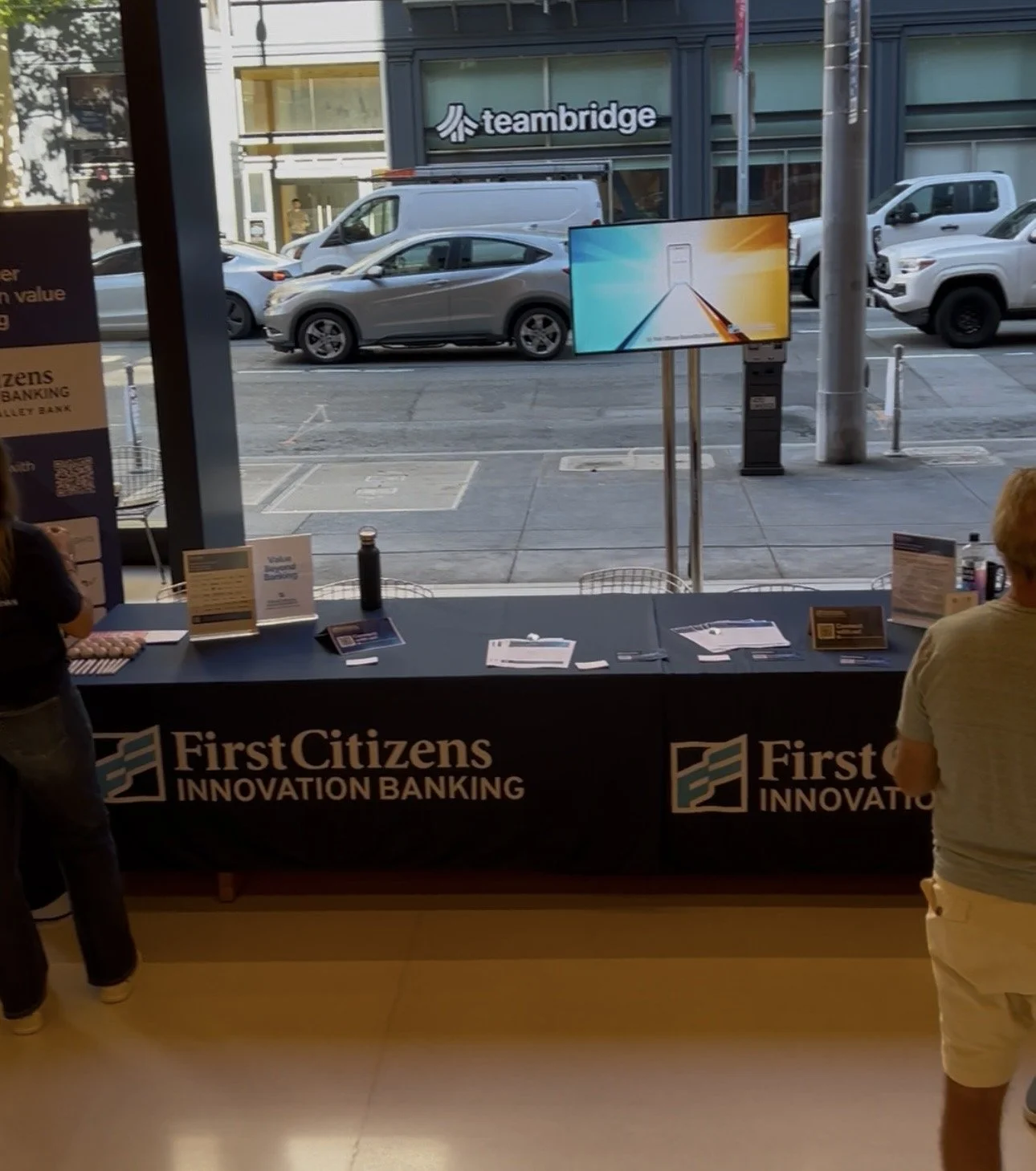 First Citizens Innovation Banking information booth with brochures and a digital display inside a storefront, overlooking a city street