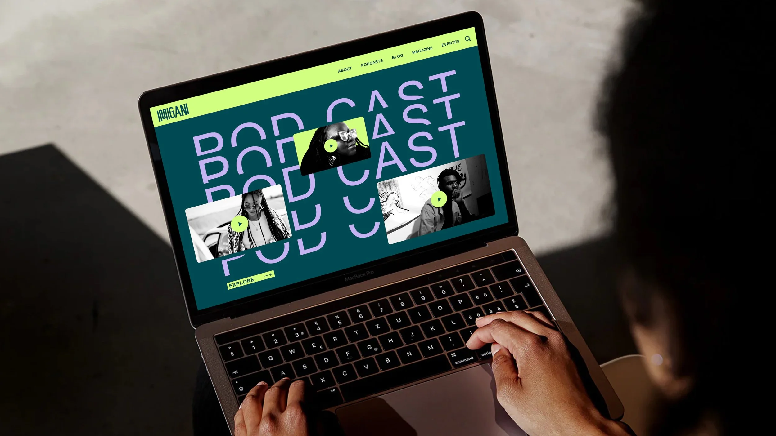 A person using a MacBook Pro laptop with a podcast website open on the screen, showing the word 'PODCAST' in purple and black-and-white images of people.