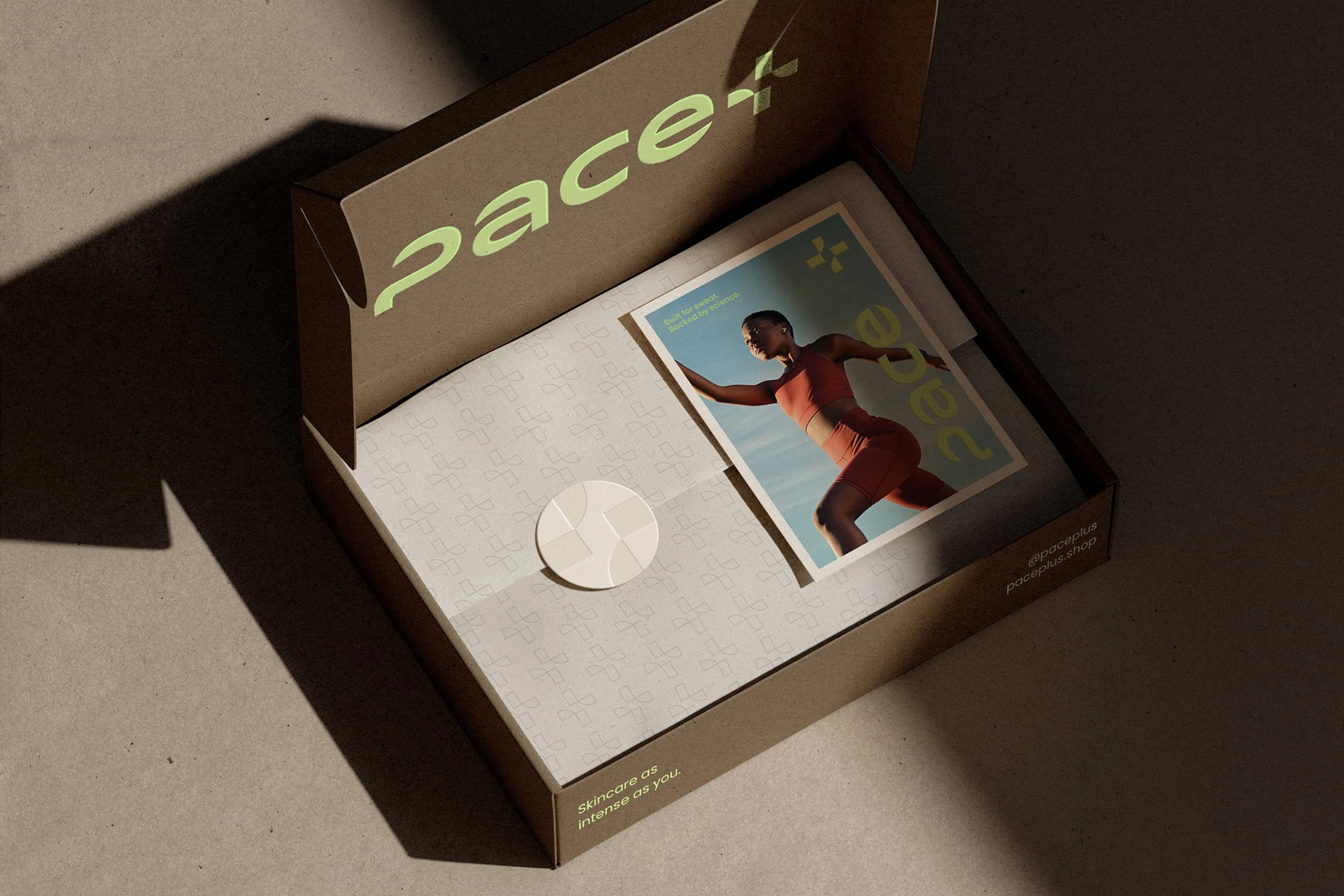 A brown box with the word 'pace+' written on it in glowing green letters, containing skincare products, a brochure with a woman exercising, and a label with social media handle @paceplus.