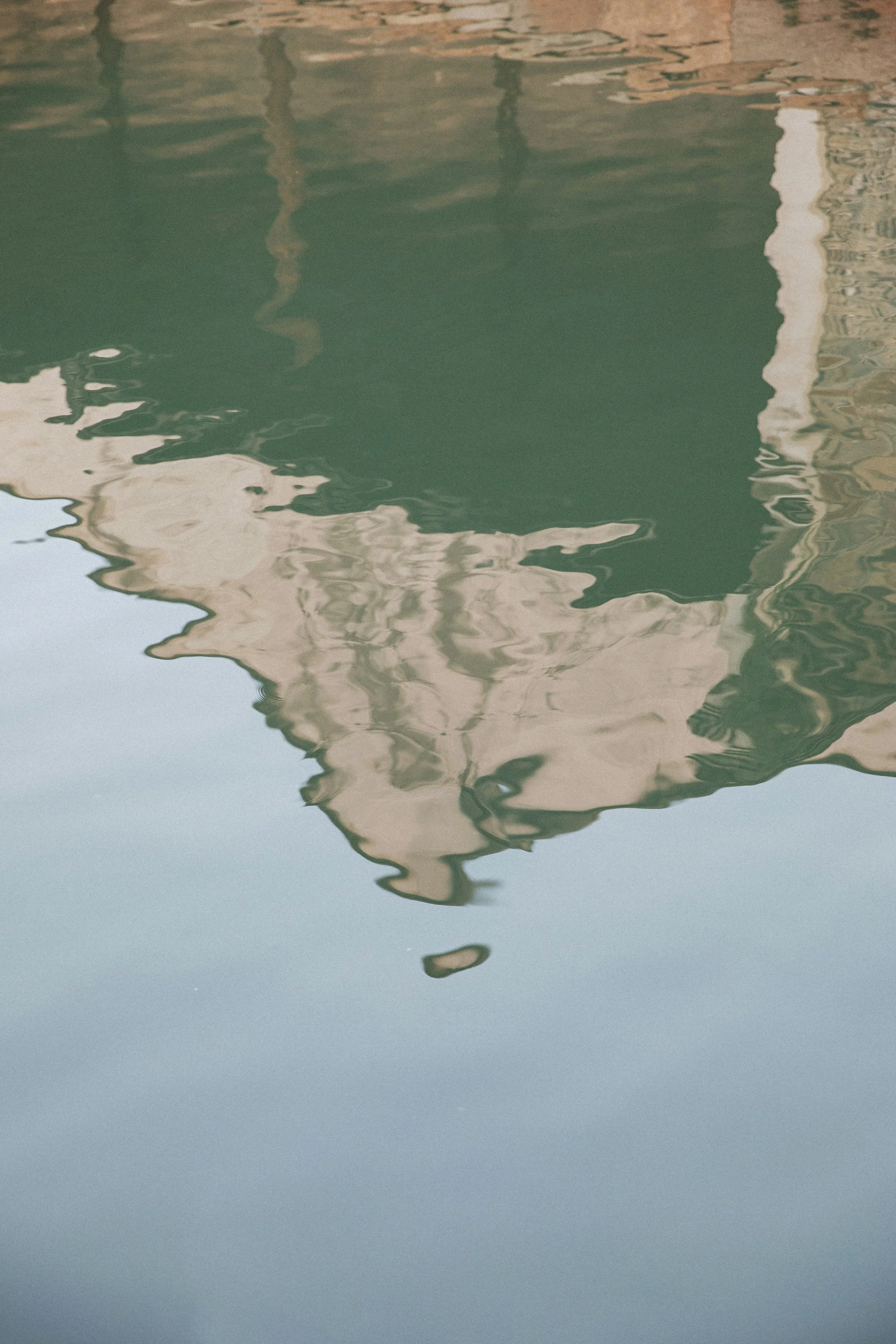 Reflection of a building in calm water, showing a distorted mirror image.