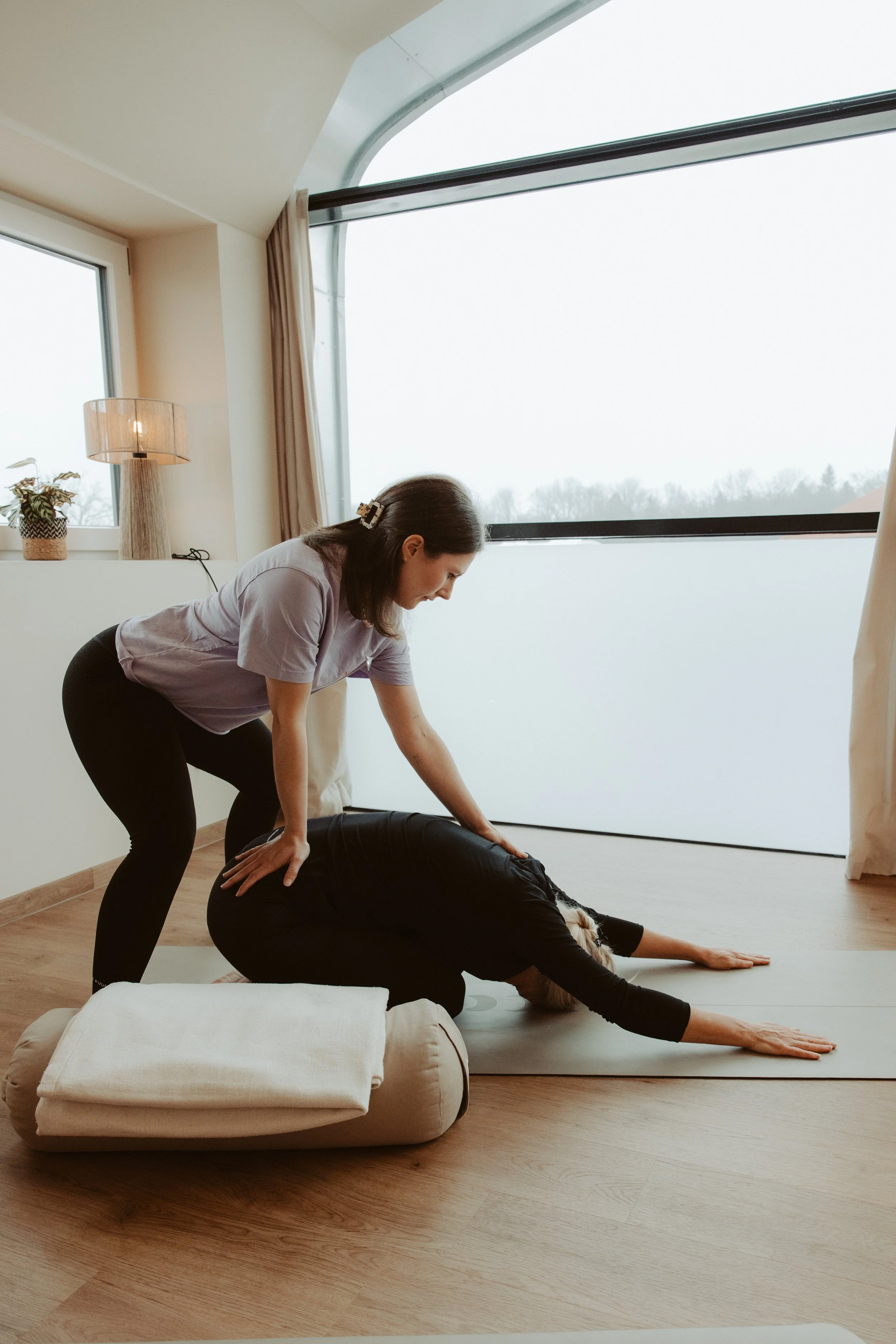 Yogalehrerin Melissa Rieder begleitet eine Teilnehmerin während eines Yoga-Workshops in Übersee am Chiemsee