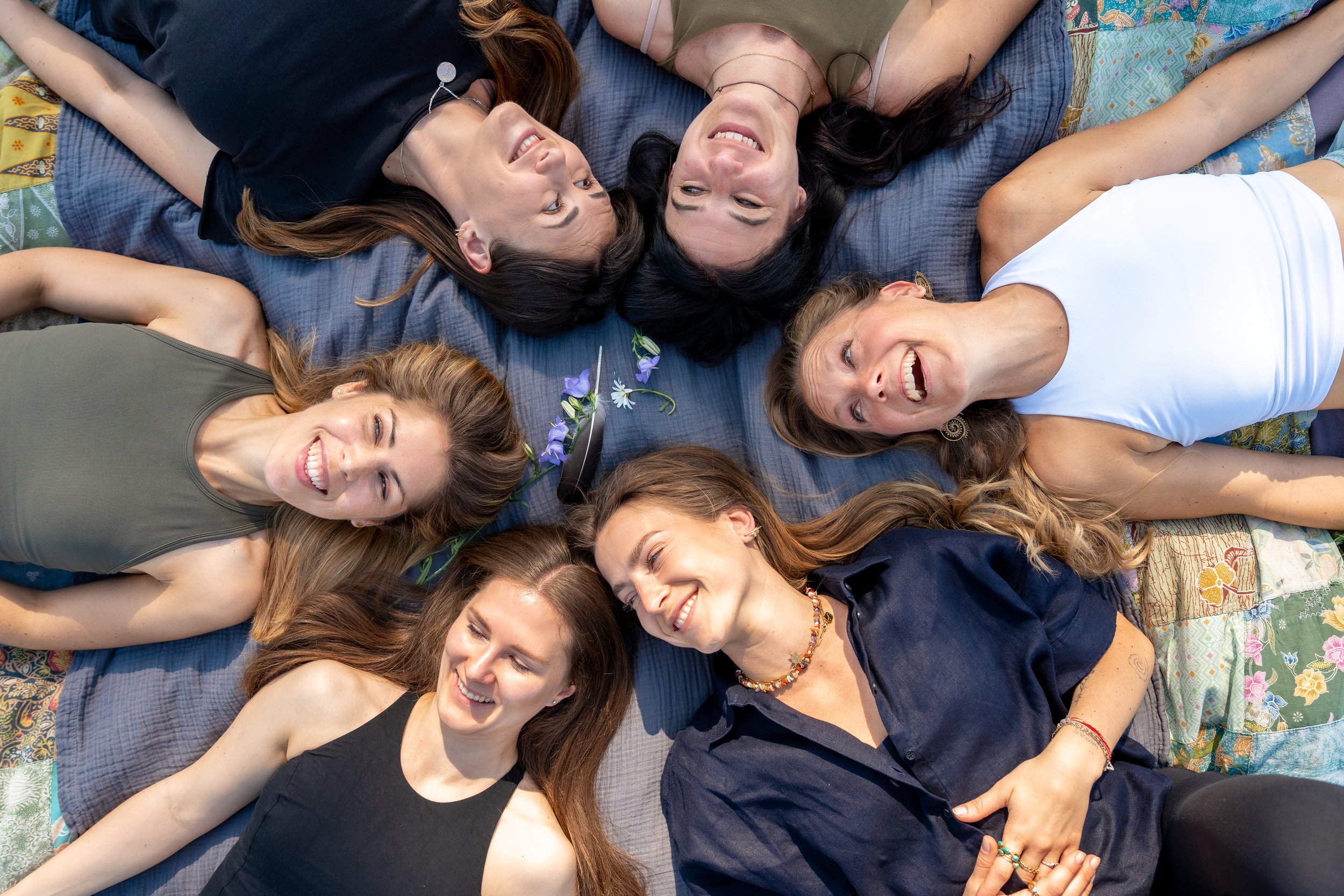 Frauen liegen gemeinsam im Kreis während eines Fem-Flows-Frauenkreises