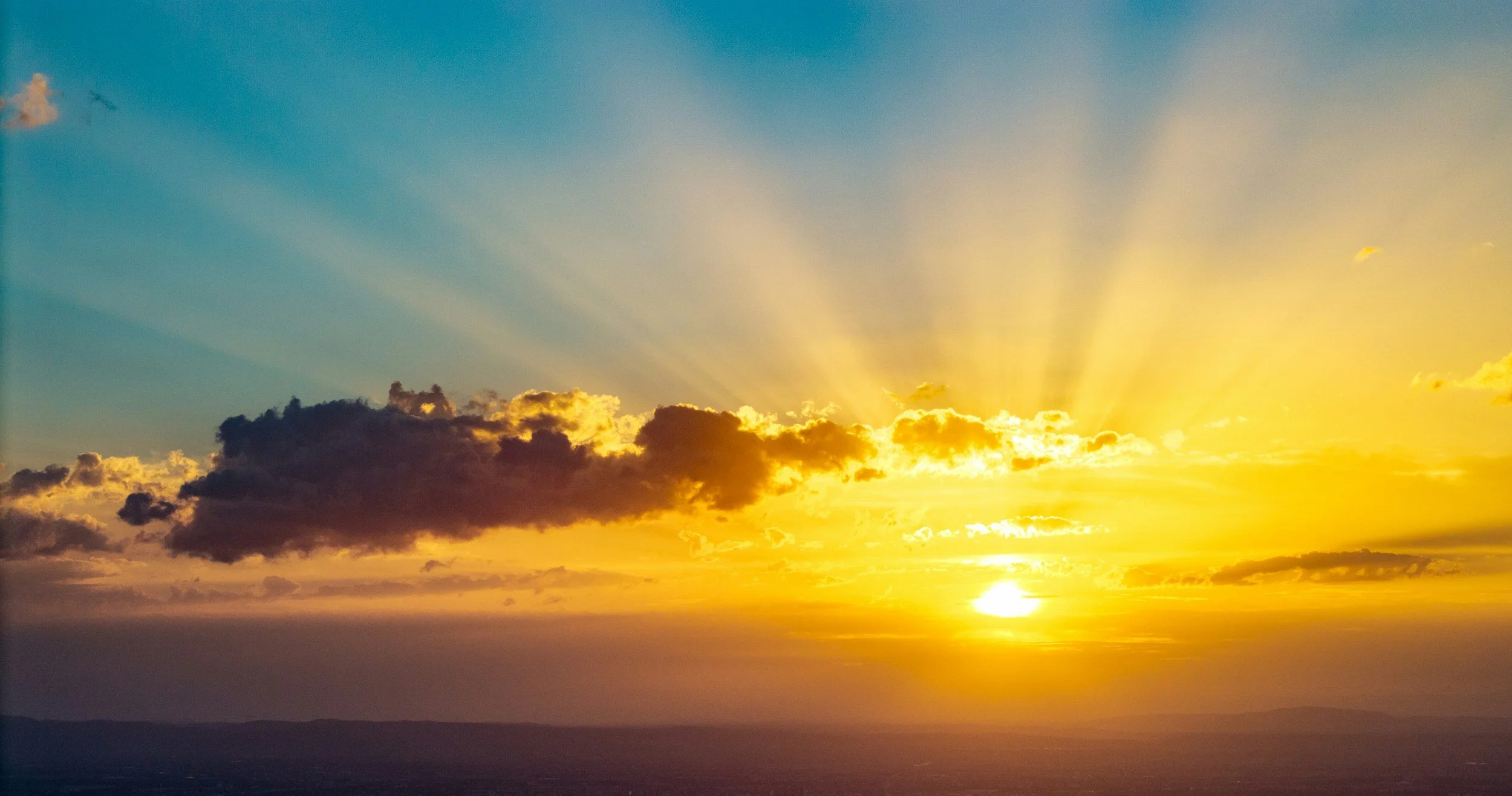 Sunset with golden rays streaming through clouds over the horizon.