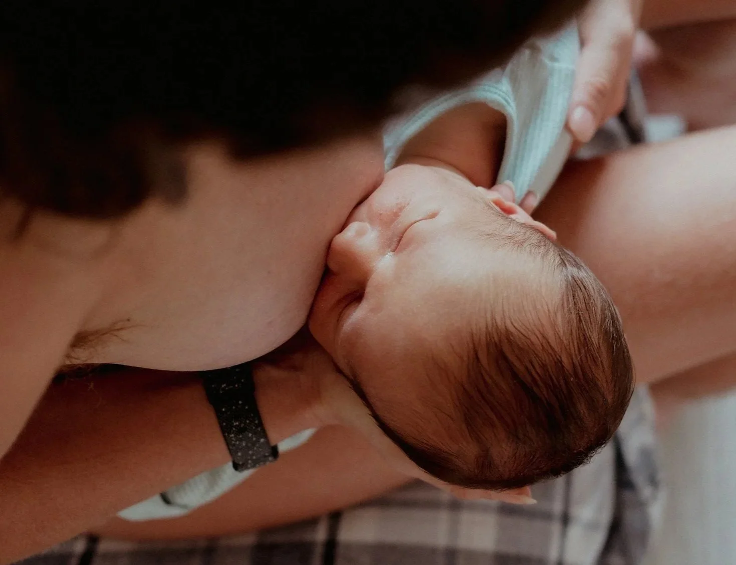 A mother breastfeeding her newborn baby in a close-up shot.