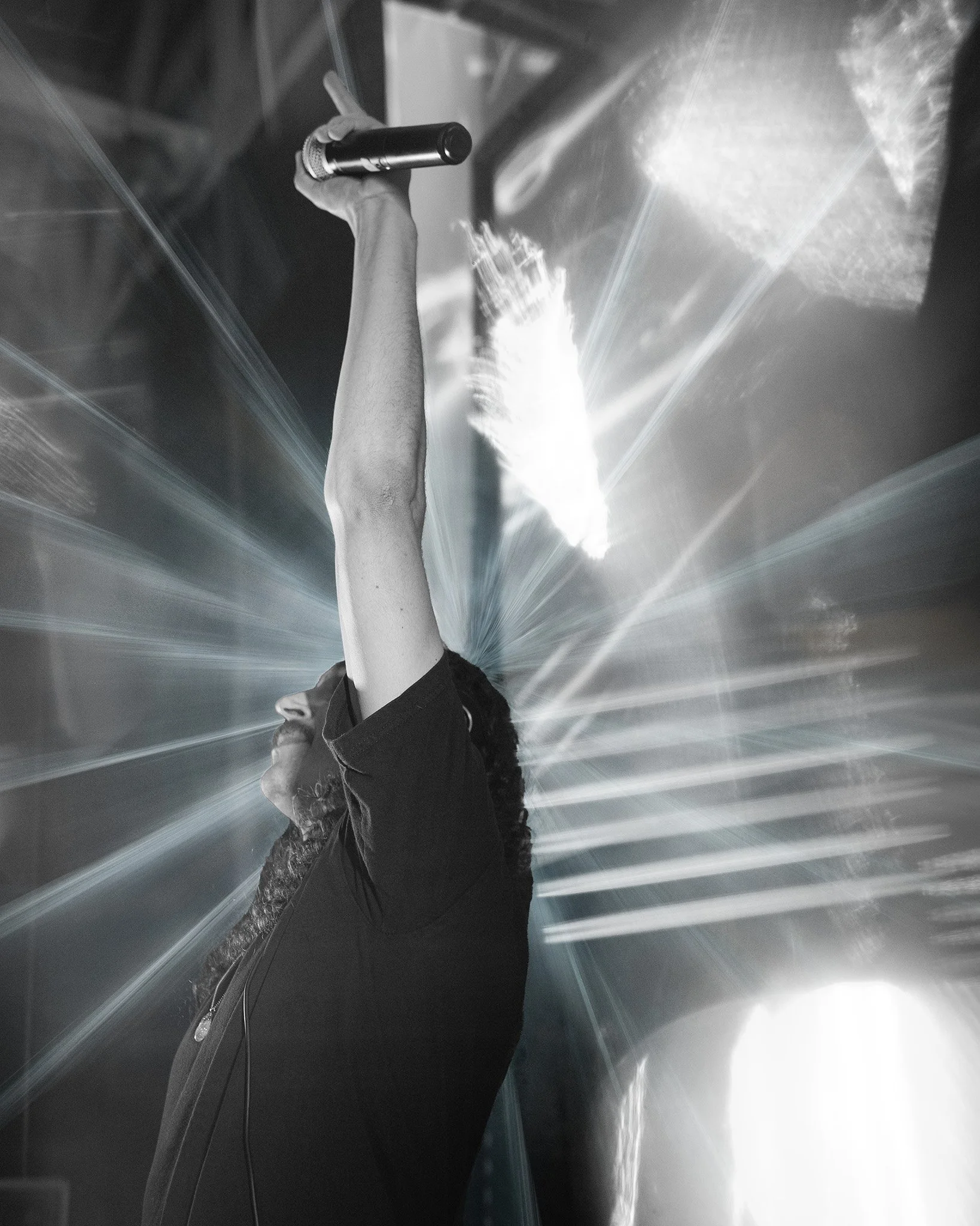 Person holding a microphone in a reflective metallic tunnel.