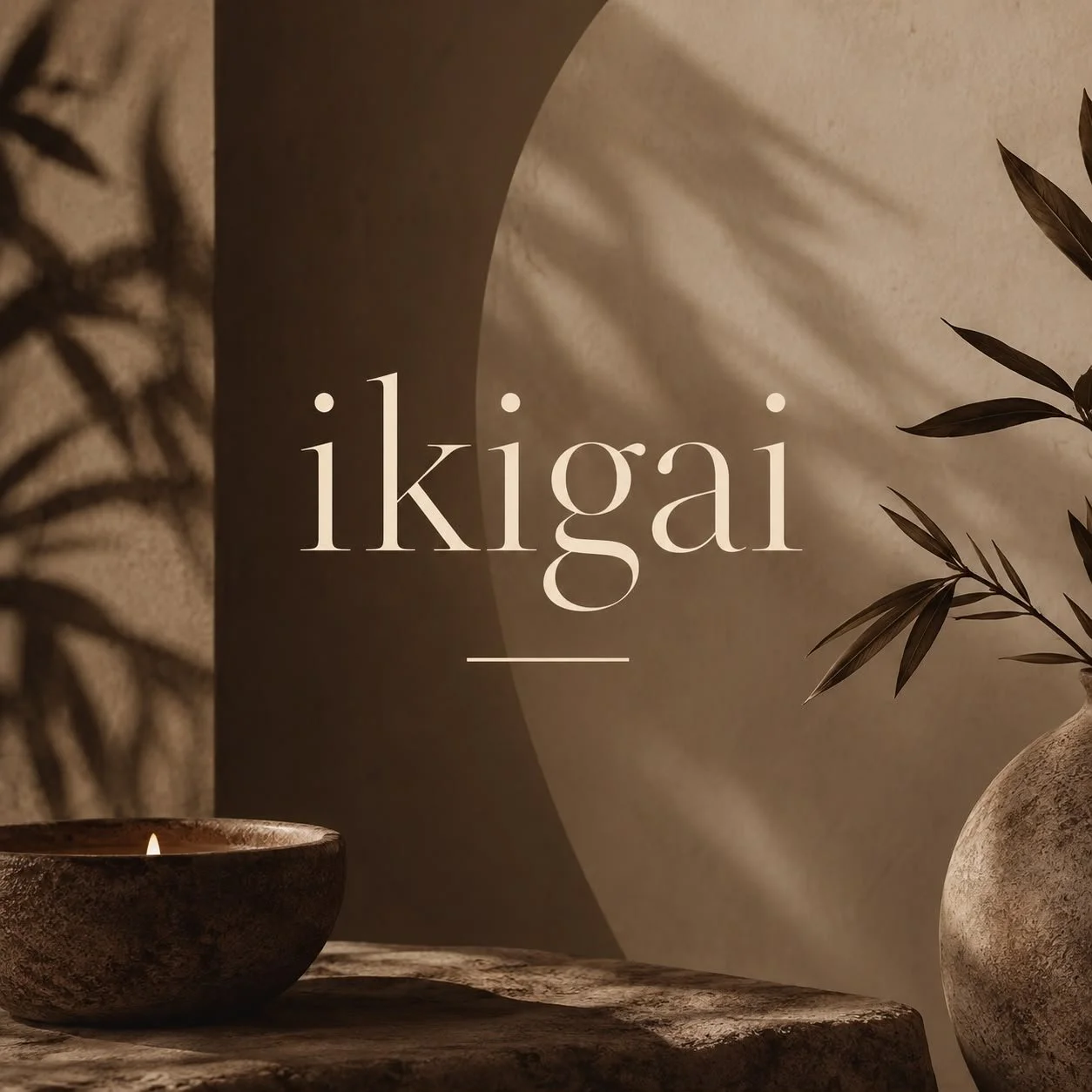 Decorative image with the word 'Ikigai' in elegant font, surrounded by shadows and natural elements like a small candle in a textured bowl, a rustic wooden surface, a stone vase, and leafy branches, with soft lighting creating a calm atmosphere.