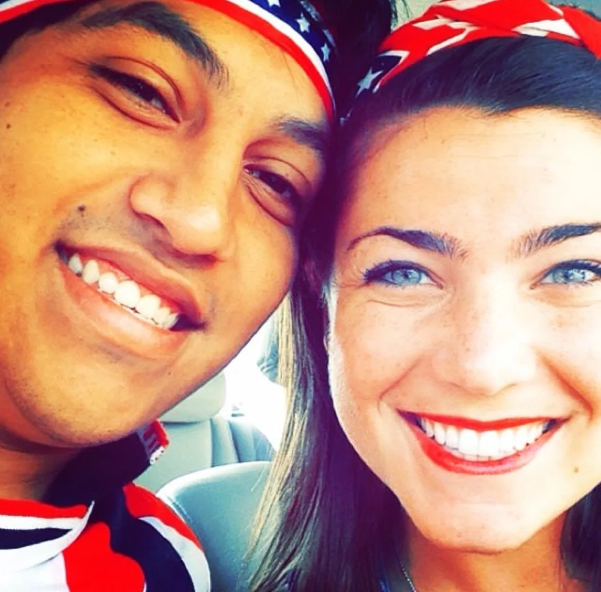 Close-up of a smiling man and woman with patriotic headbands, showing their faces and expressions.