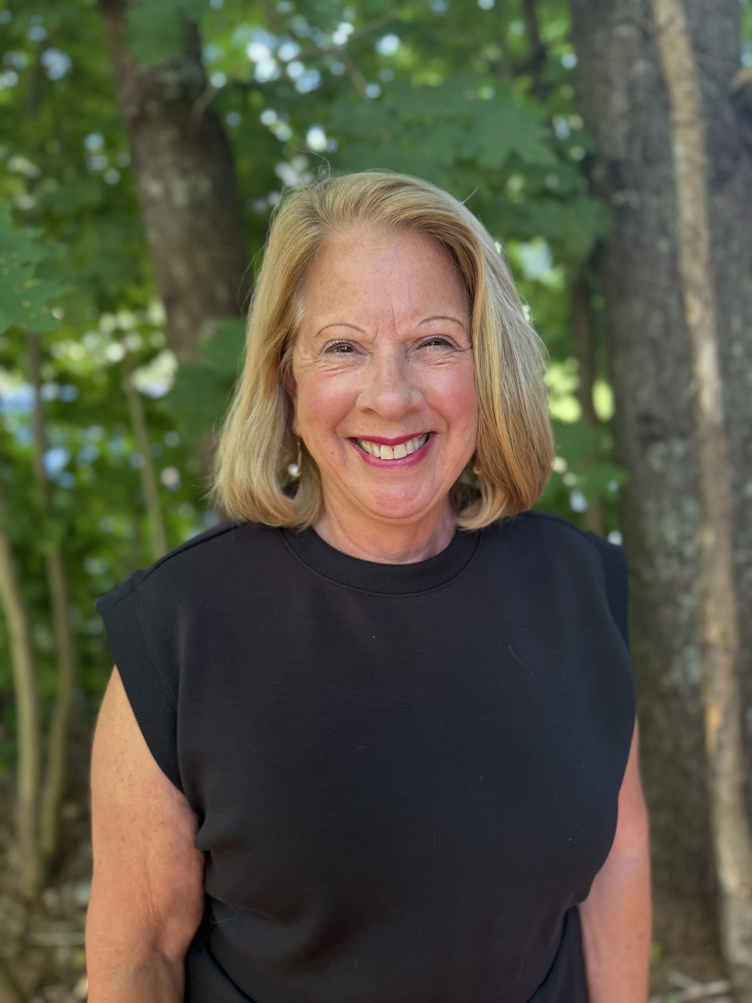 Becky Lynn-Crockford, CPA, founder of Waggle, smiling outdoors in front of green trees.