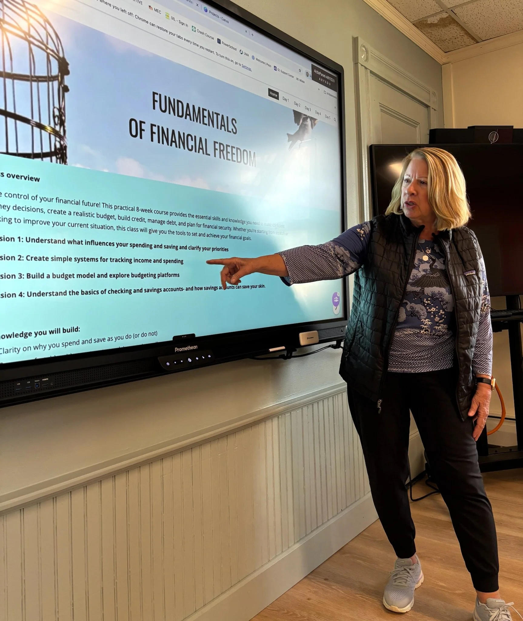 Instructor pointing to a financial education slide on a large screen while teaching a class.