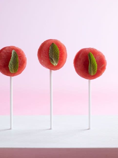 Watermelon Mint Lolipops arranged in a row against a light pink background.