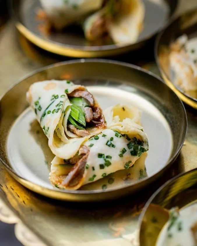 Steamed dumplings with sliced beef and scallions on a silver plate.