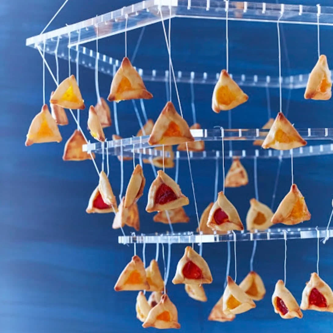 Miniature triangular pastries suspended from a tiered presentation stand.