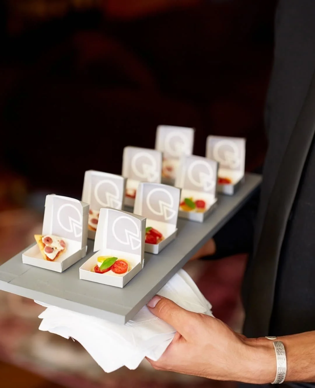Miniature pizza and tomato-basil appetizers presented in individual boxes.