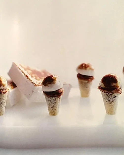 Miniature ice cream cone desserts with chocolate garnish.