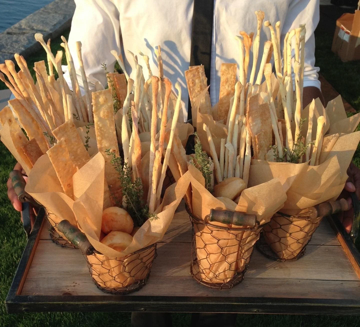 Assorted breads and flatbreads presented in woven baskets on a wooden tray.