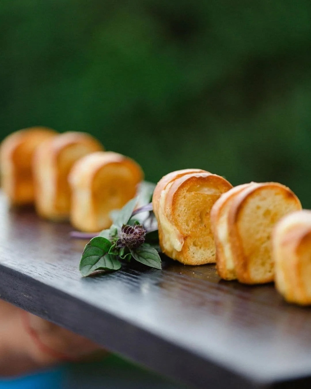 Miniature savory cannoli arranged on a wooden serving board.