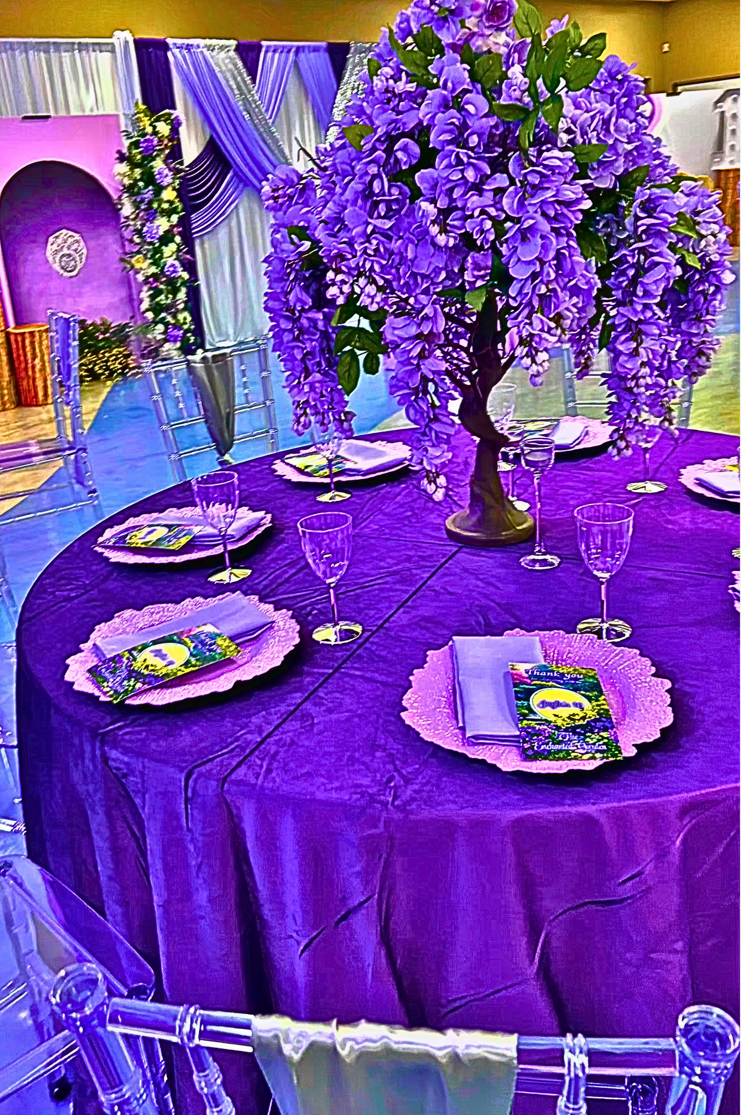 An Enchanted Sweet 16 brought to life with tree centerpieces, layered purple tones, and silver accents.   A life‑sized butterfly and a blooming garden backdrop complete this dreamy, storybook inspired celebration.
