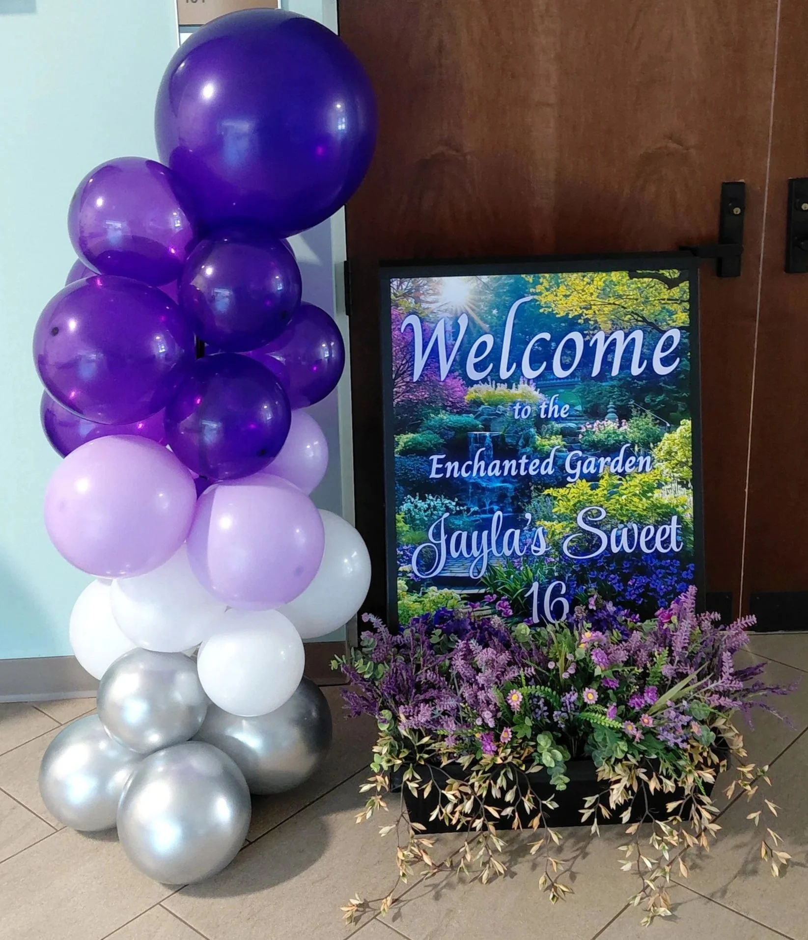 An Enchanted Sweet 16 brought to life with tree centerpieces, layered purple tones, and silver accents.   A life‑sized butterfly and a blooming garden backdrop complete this dreamy, storybook inspired celebration.