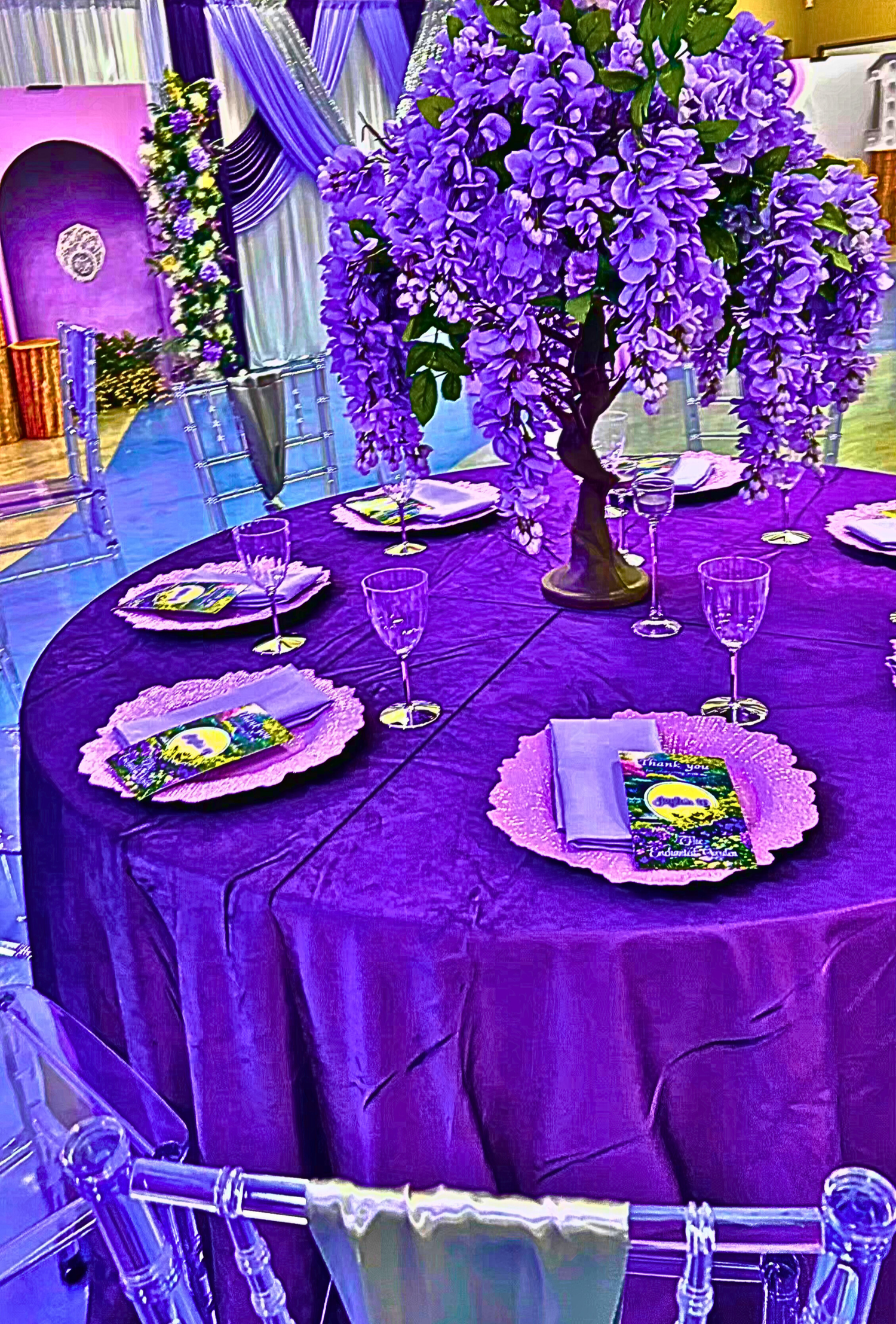 An Enchanted Sweet 16 brought to life with tree centerpieces, layered purple tones, and silver accents.   A life‑sized butterfly and a blooming garden backdrop complete this dreamy, storybook inspired celebration.