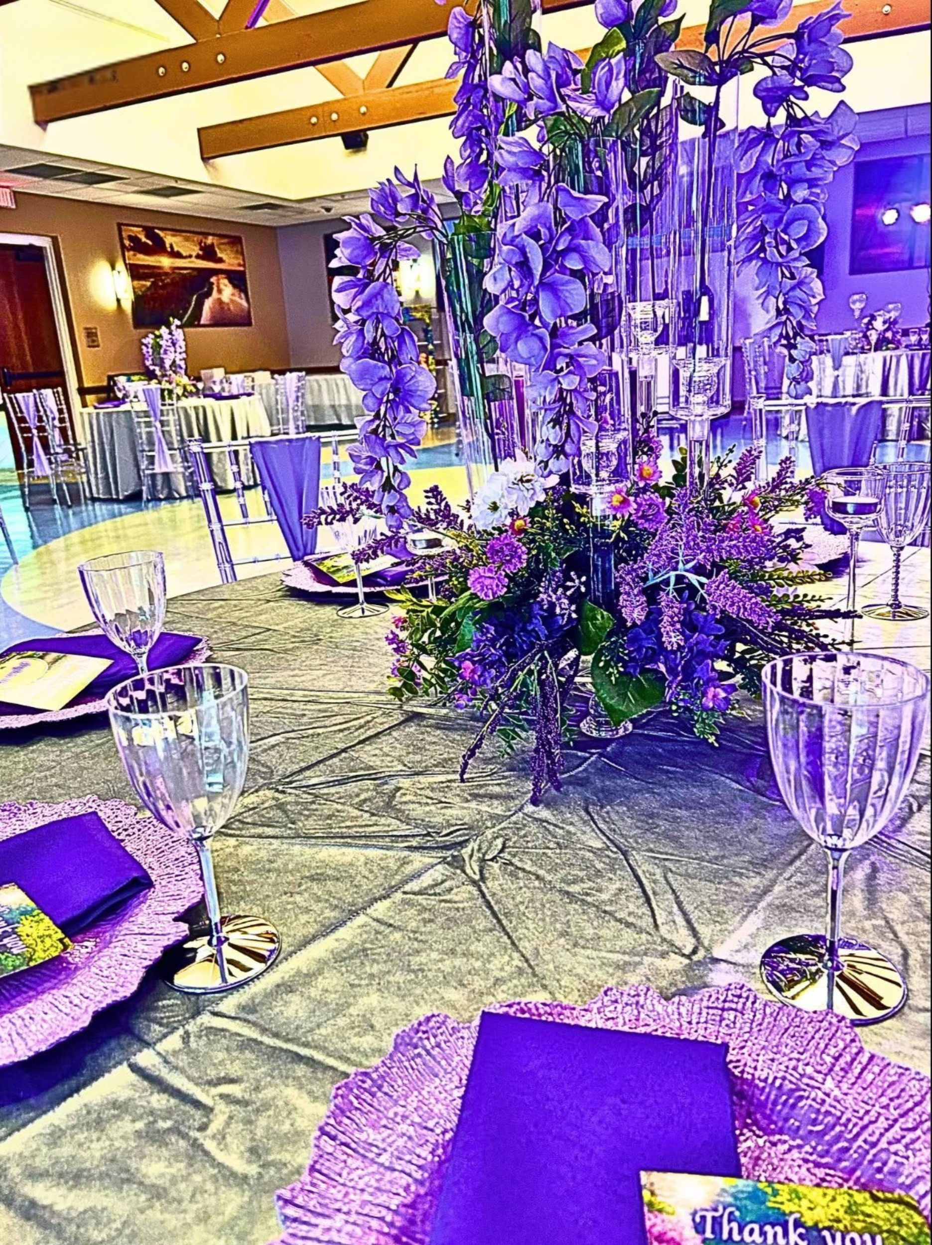 An Enchanted Sweet 16 brought to life with tree centerpieces, layered purple tones, and silver accents.   A life‑sized butterfly and a blooming garden backdrop complete this dreamy, storybook inspired celebration.