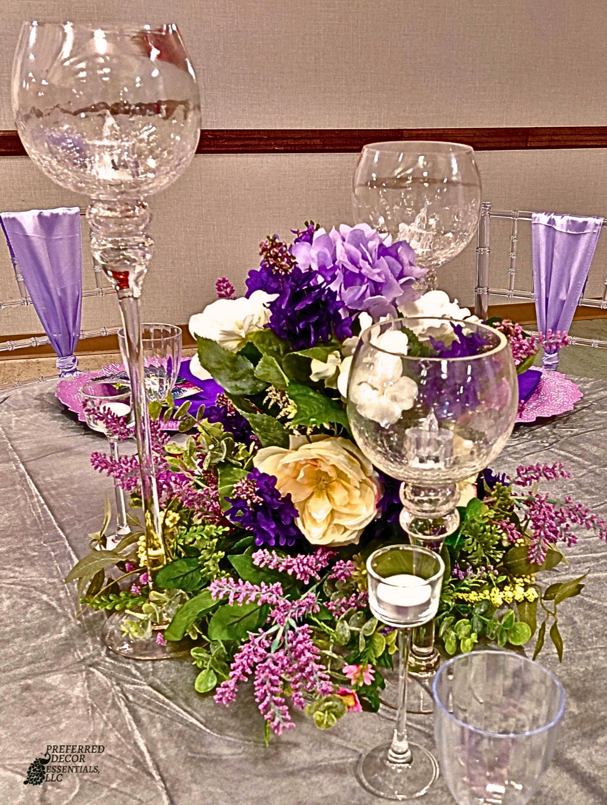 An Enchanted Sweet 16 brought to life with tree centerpieces, layered purple tones, and silver accents.   A life‑sized butterfly and a blooming garden backdrop complete this dreamy, storybook inspired celebration.