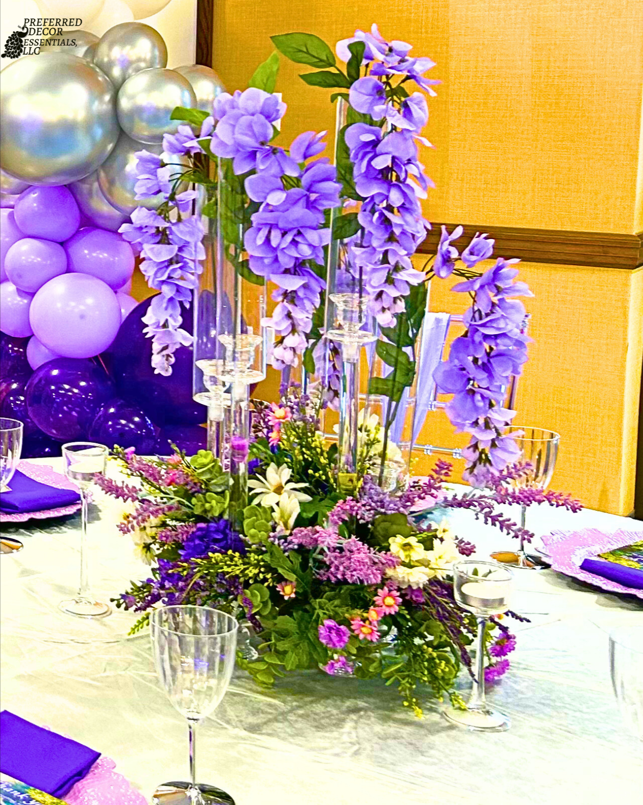 An Enchanted Sweet 16 brought to life with tree centerpieces, layered purple tones, and silver accents.   A life‑sized butterfly and a blooming garden backdrop complete this dreamy, storybook inspired celebration.