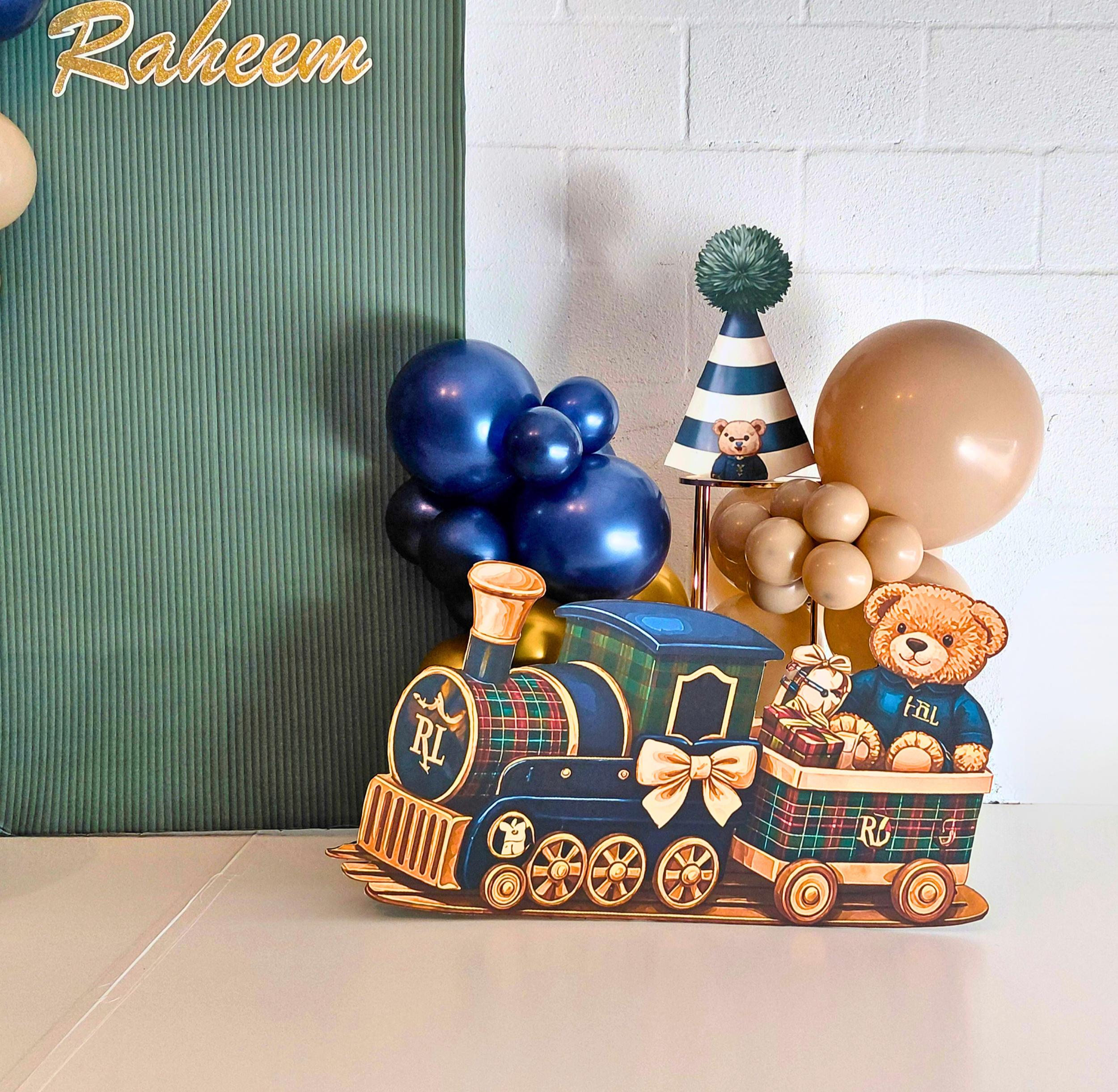 A charming Teddy Bear–themed 5th birthday celebration designed with bold blue, tan, and gold color‑blocking.  A life‑sized bear, mini train, birthday hat, and number 5 prop highlight the theme and complete the cohesive look.