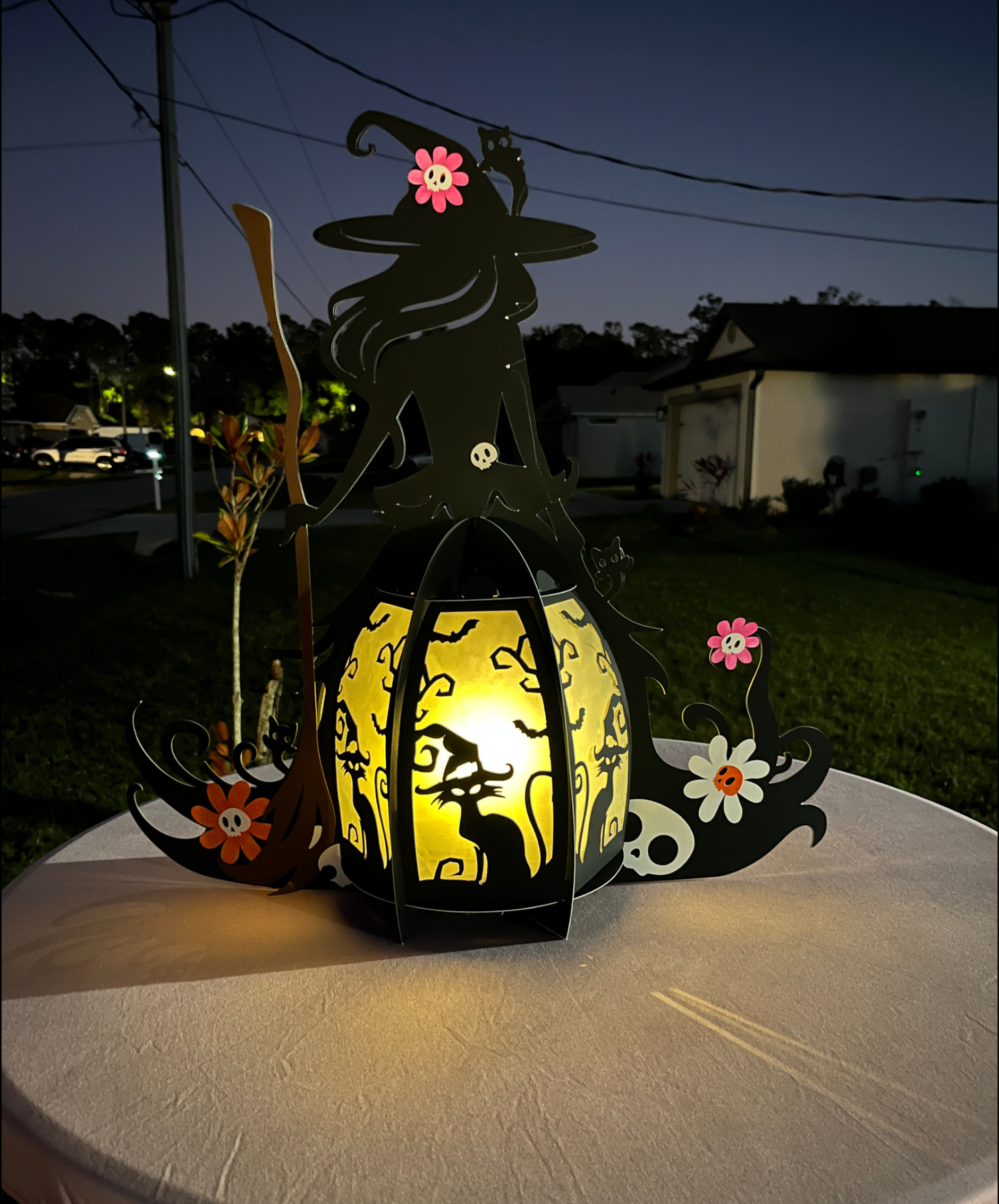 A Halloween themed birthday celebration featuring a large witch centerpiece illuminated to create a glowing effect in the dark, spooky atmosphere.