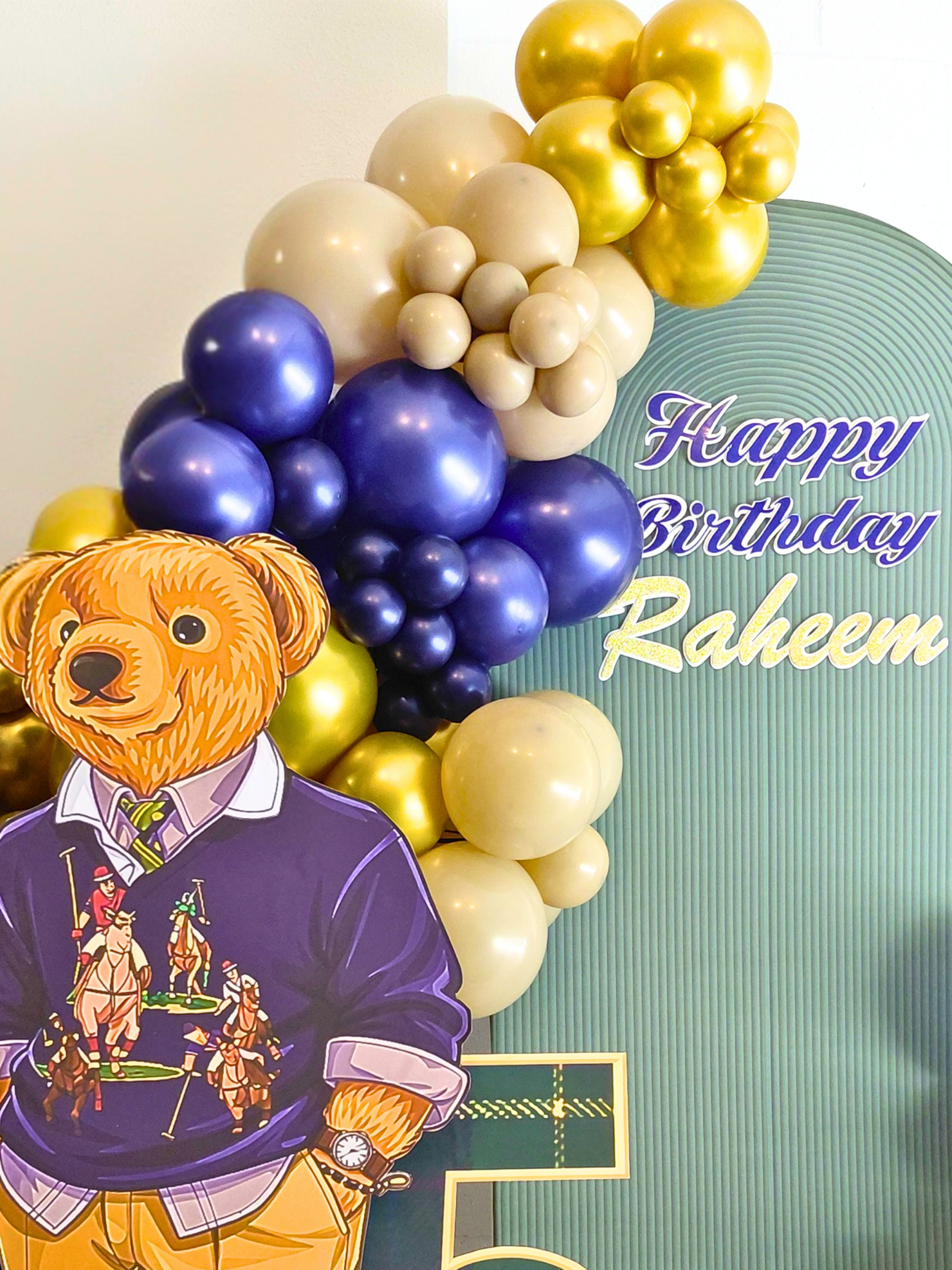 A charming Teddy Bear–themed 5th birthday celebration designed with bold blue, tan, and gold color‑blocking.  A life‑sized bear, mini train, birthday hat, and number 5 prop highlight the theme and complete the cohesive look.