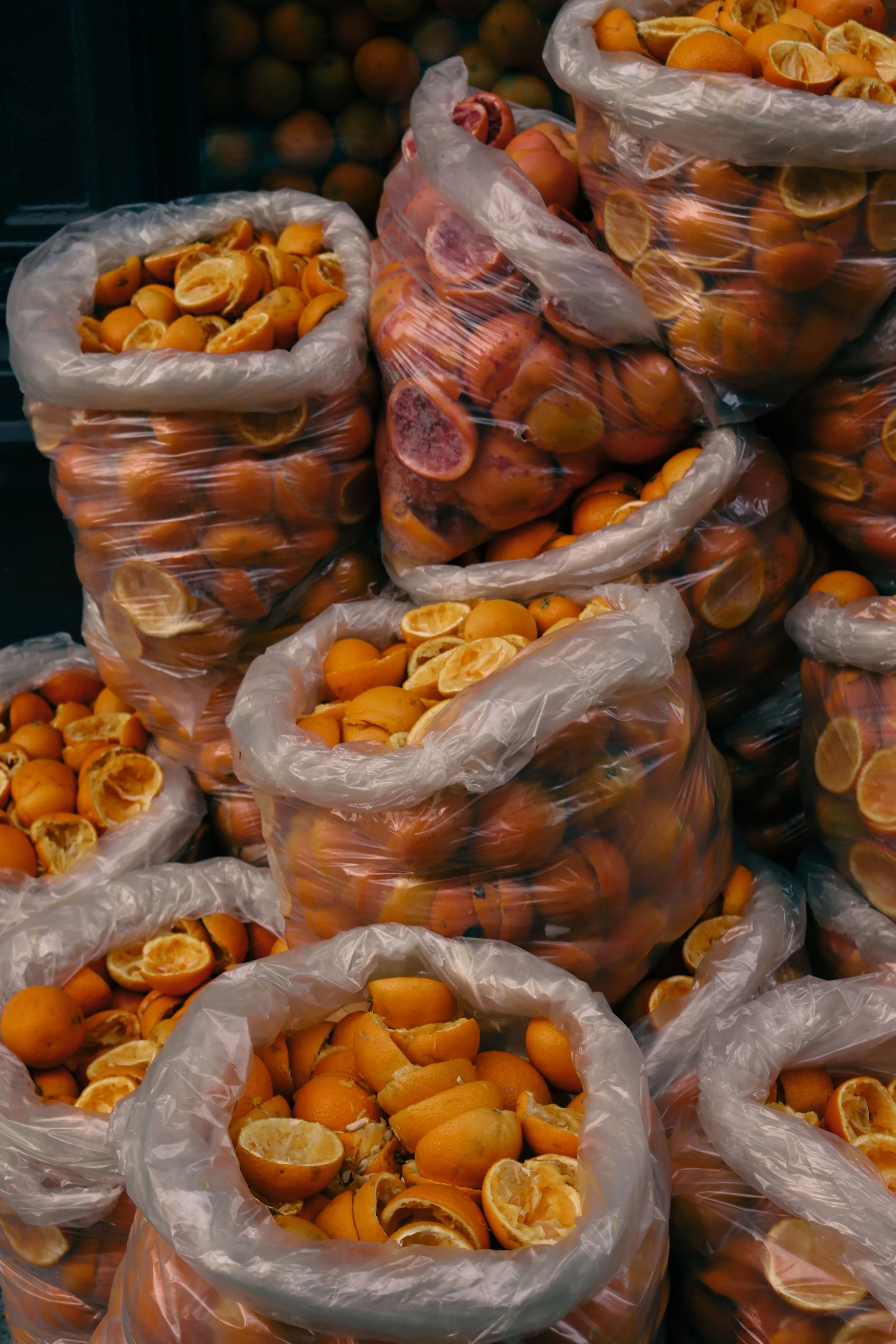 Bags of peeled and halved oranges stacked in plastic bags at a market or store.