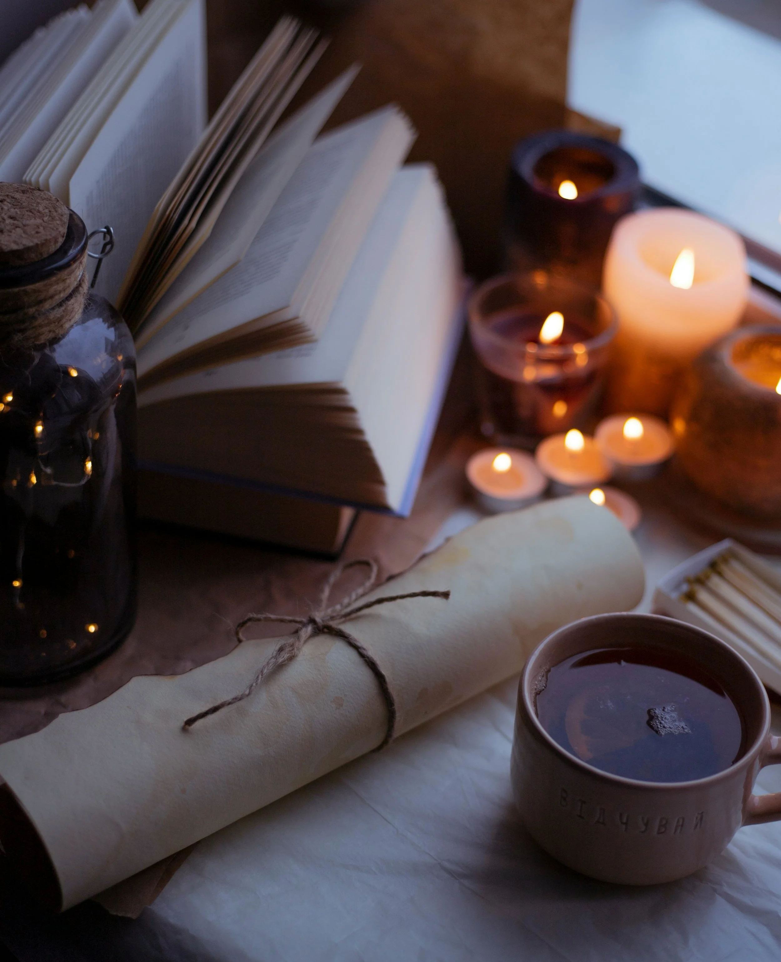 aesthetic photo of scroll, books, glass bottle, and candles