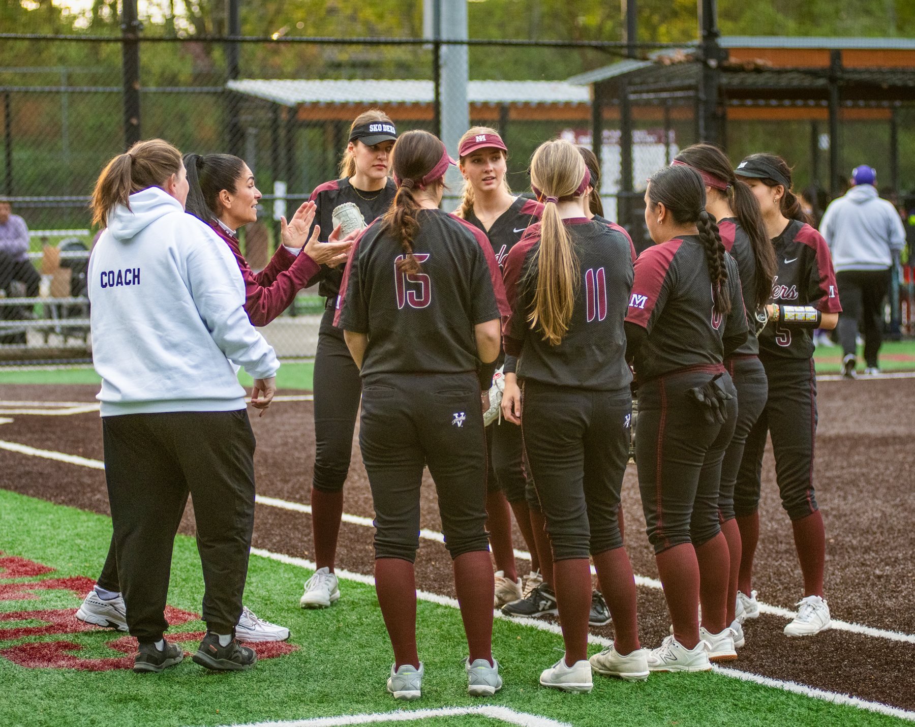 MIHS softball players and coaches huddle together.