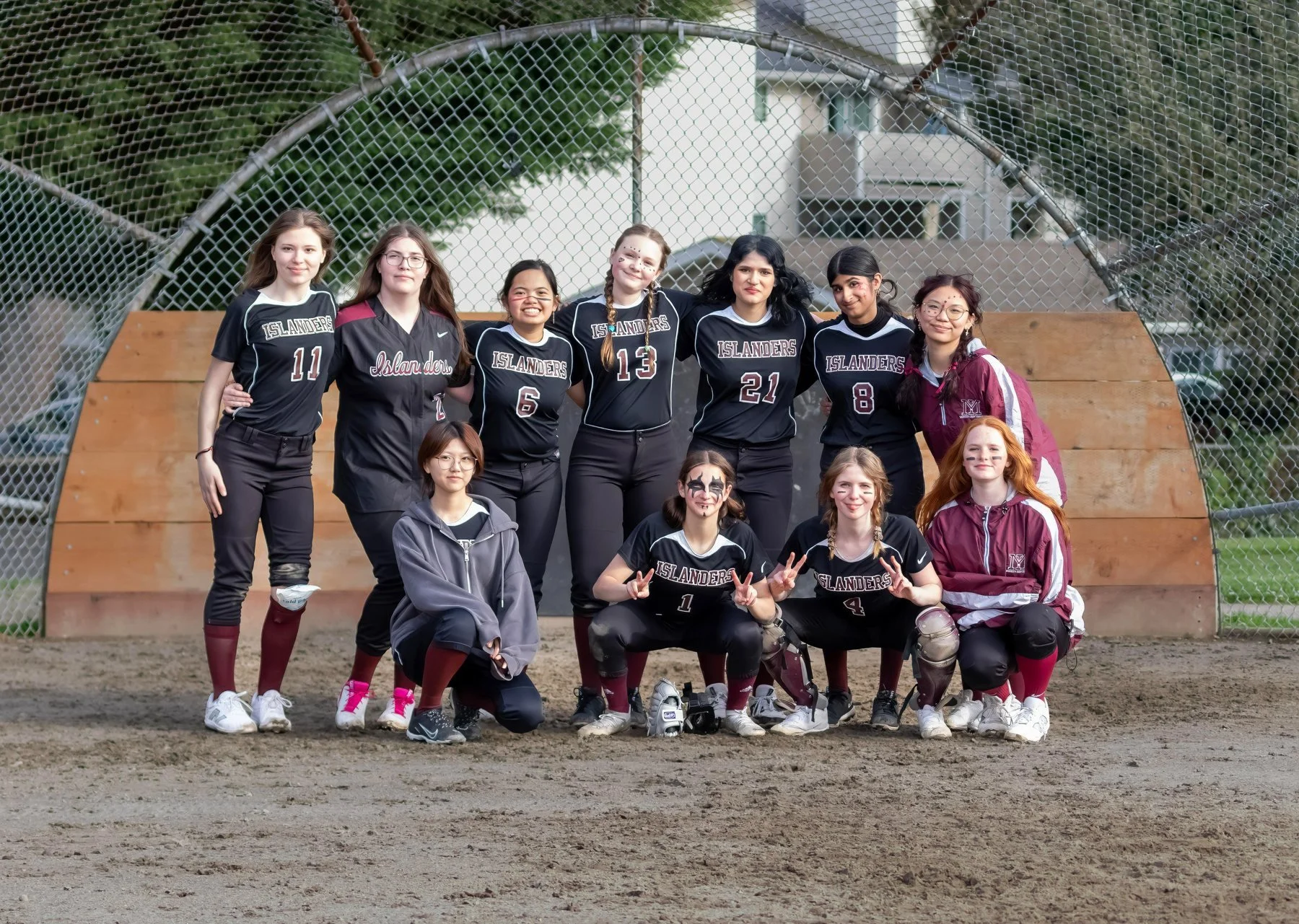 Mercer Island softball team poses together beside the backstop.