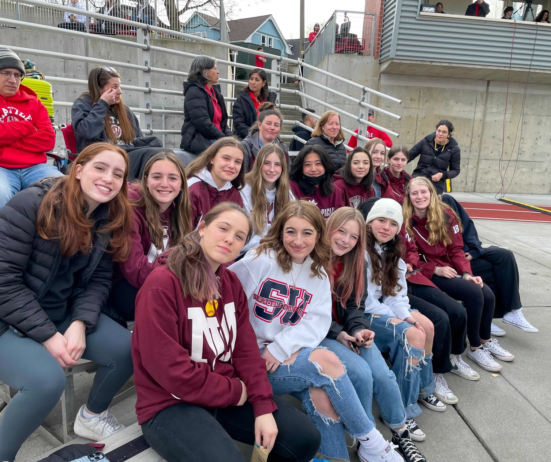Mercer Island softball teammates pose together in stadium seats.