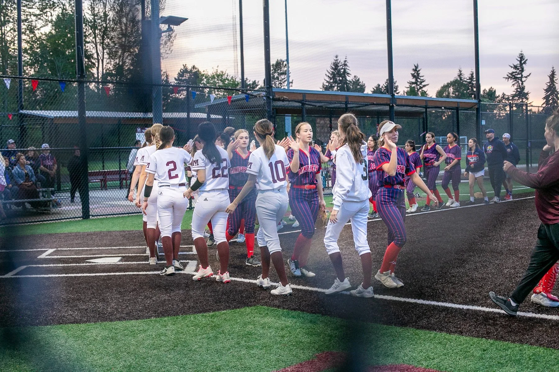 Softball teams exchange postgame high-fives on the field.