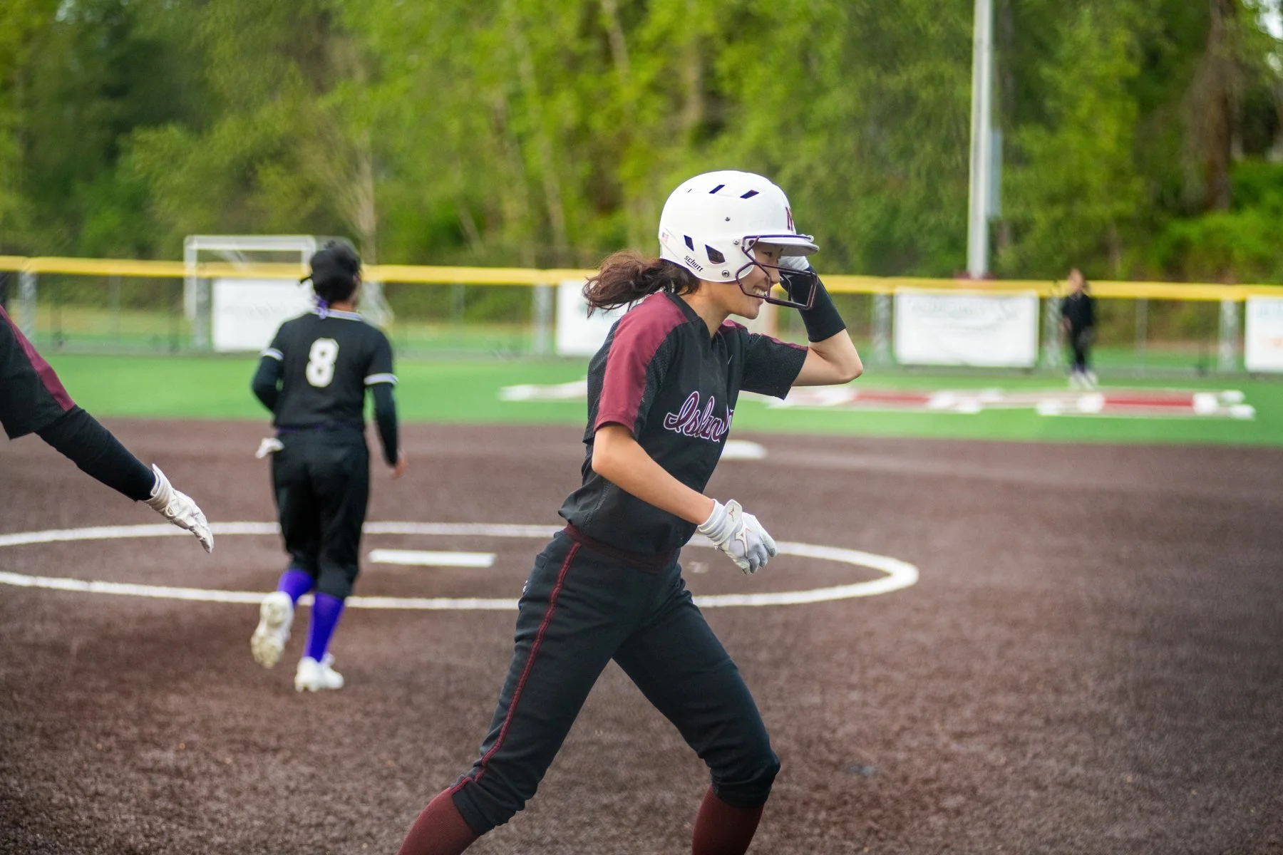 Helmeted Islander softball runner jogs along the baseline.
