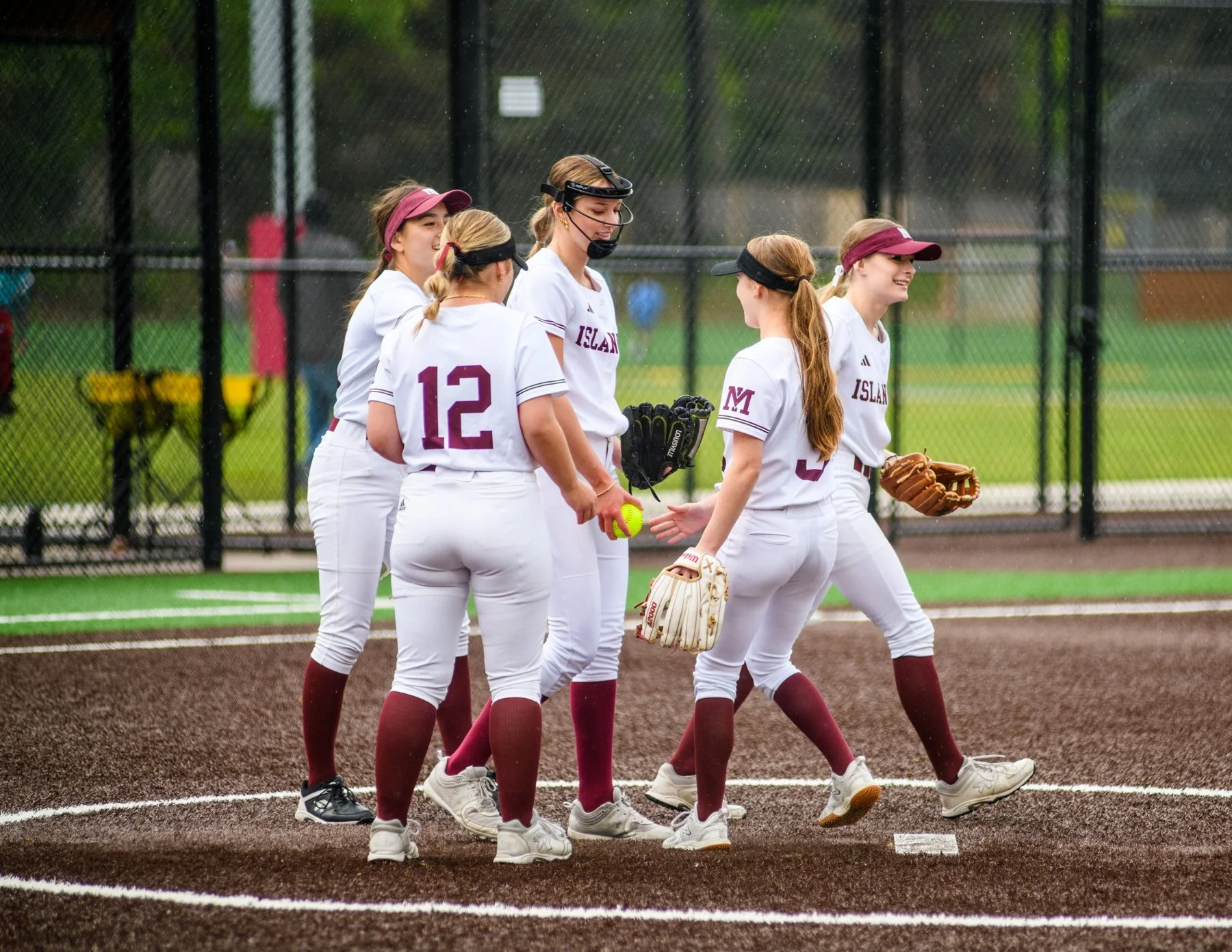 MIHS softball players gather together on the infield.