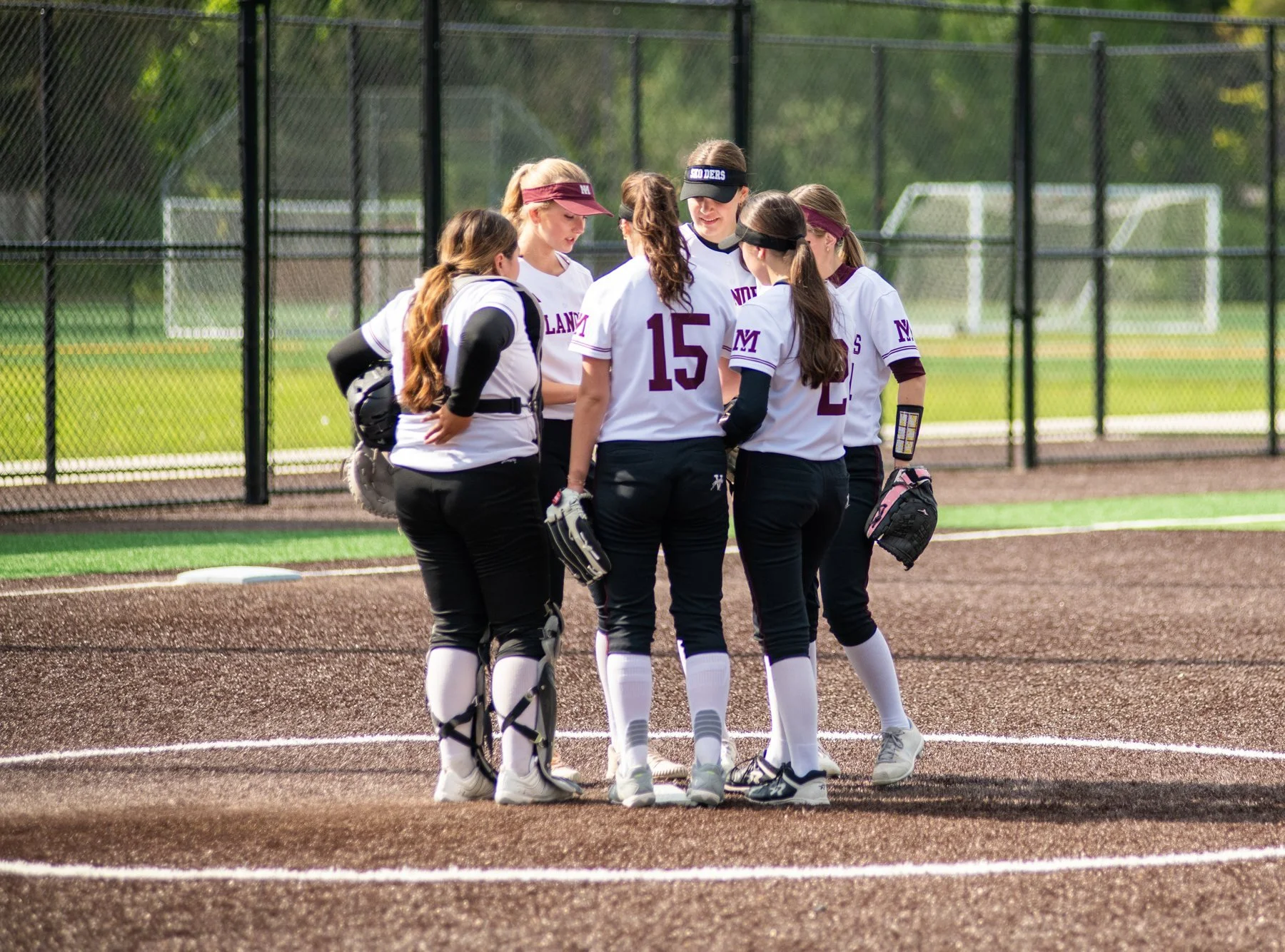MIHS softball players huddle together on the infield.