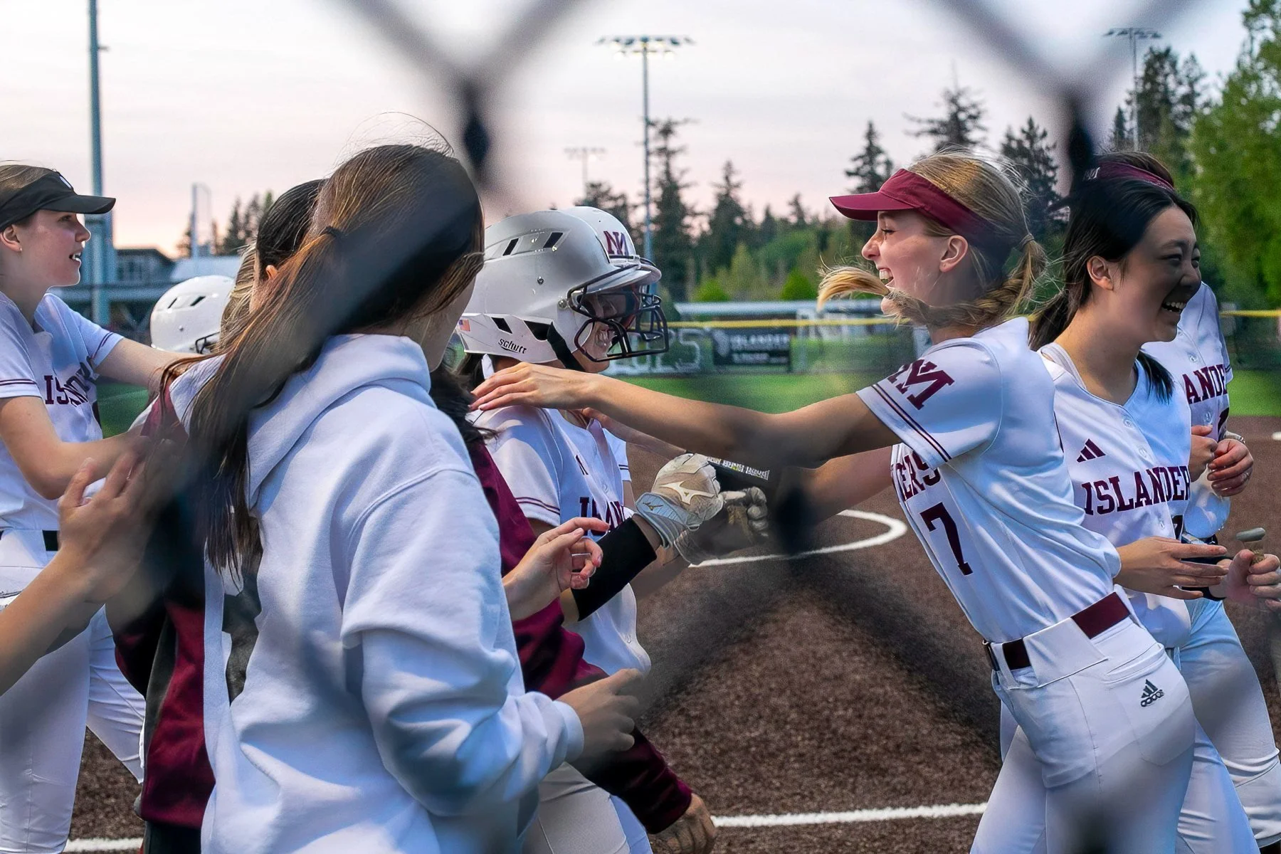 MIHS softball teammates celebrate together near the dugout.