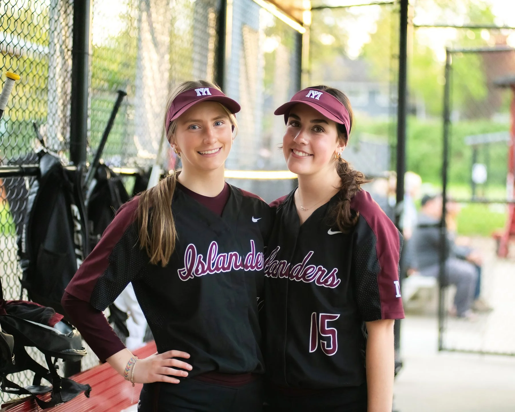 Two MIHS softball teammates stand together in the dugout.