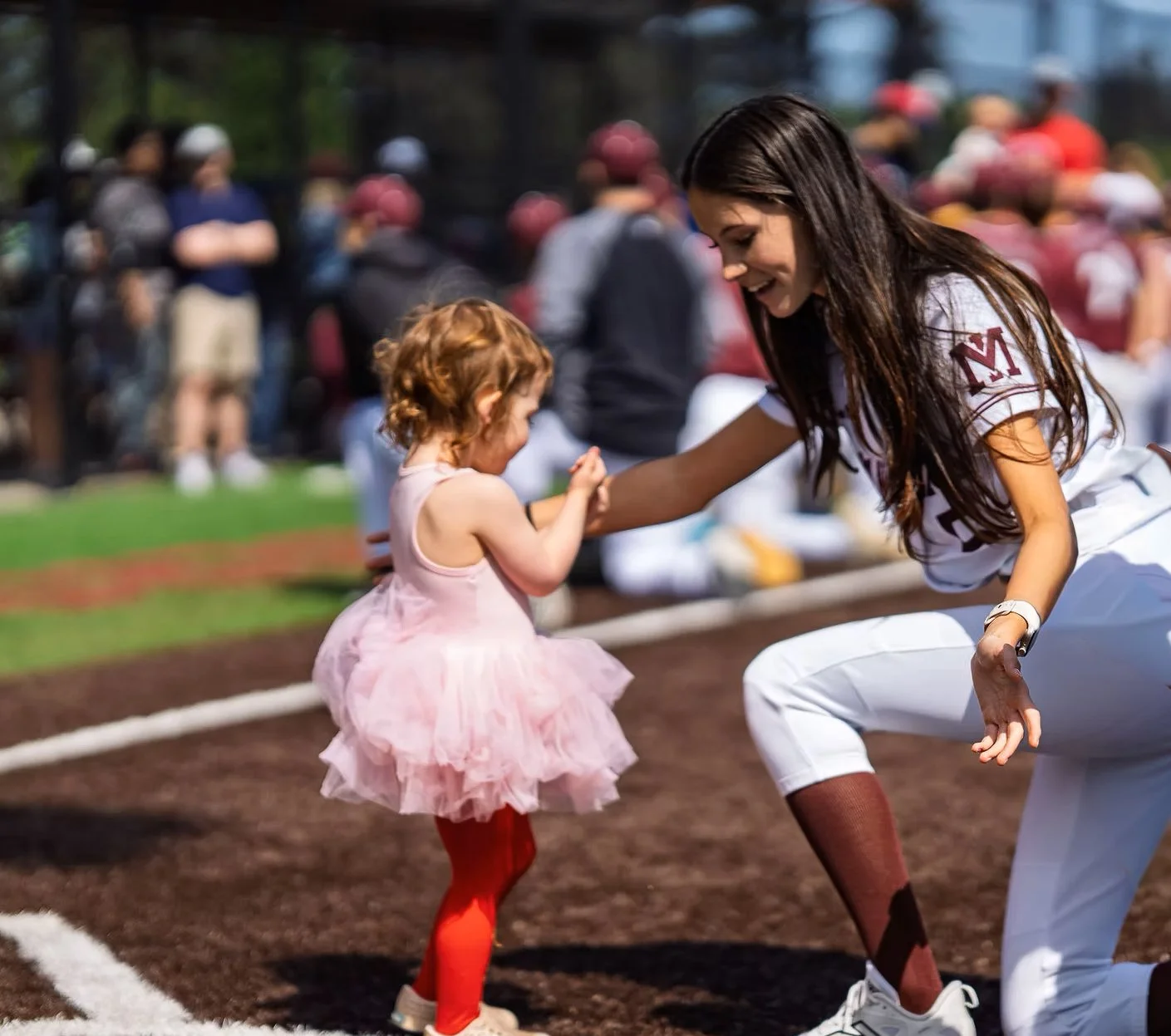 Mercer Island softball player high-fives a young child on the field.