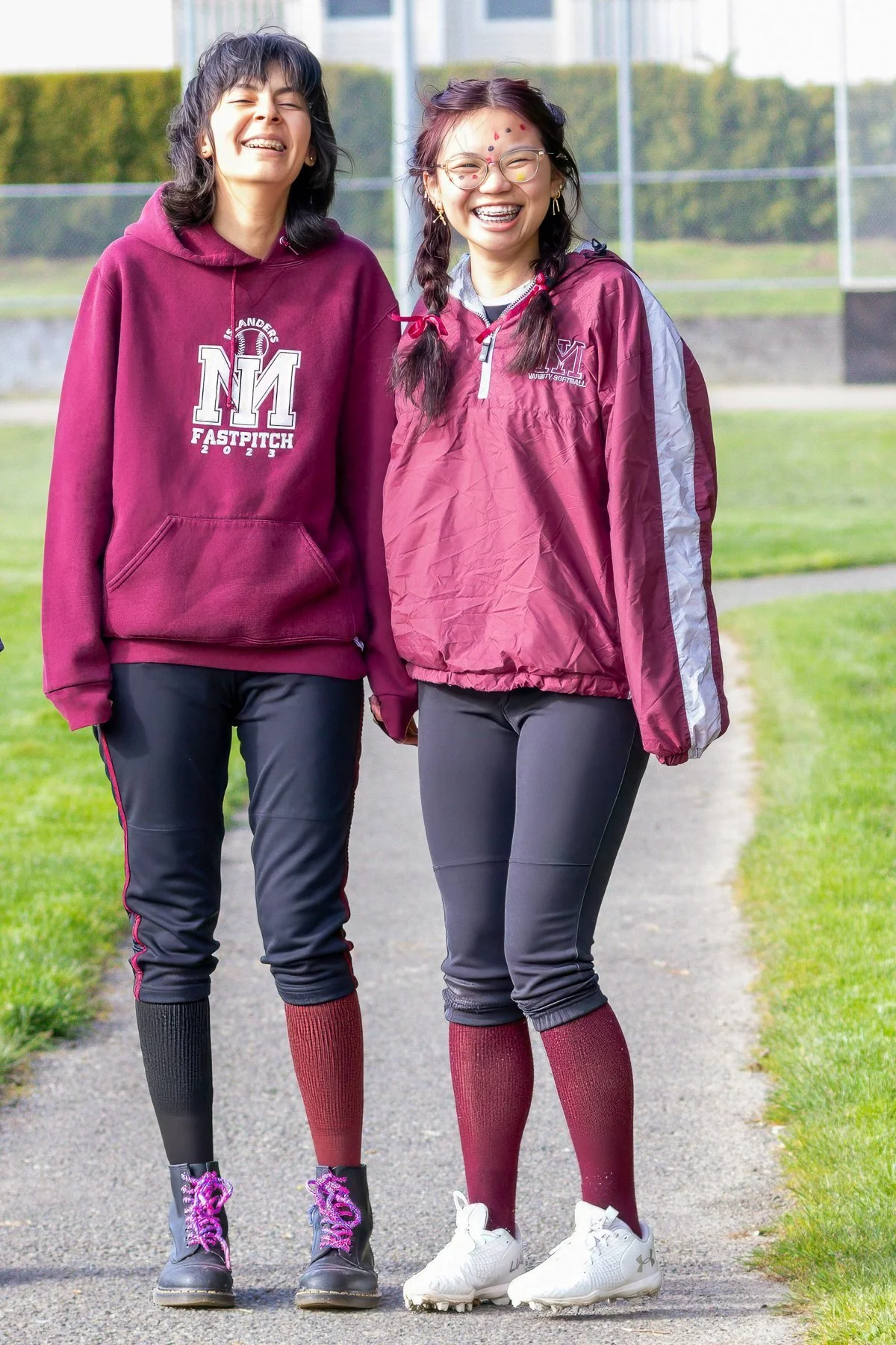 Two Mercer Island softball teammates pose in maroon sweatshirts.