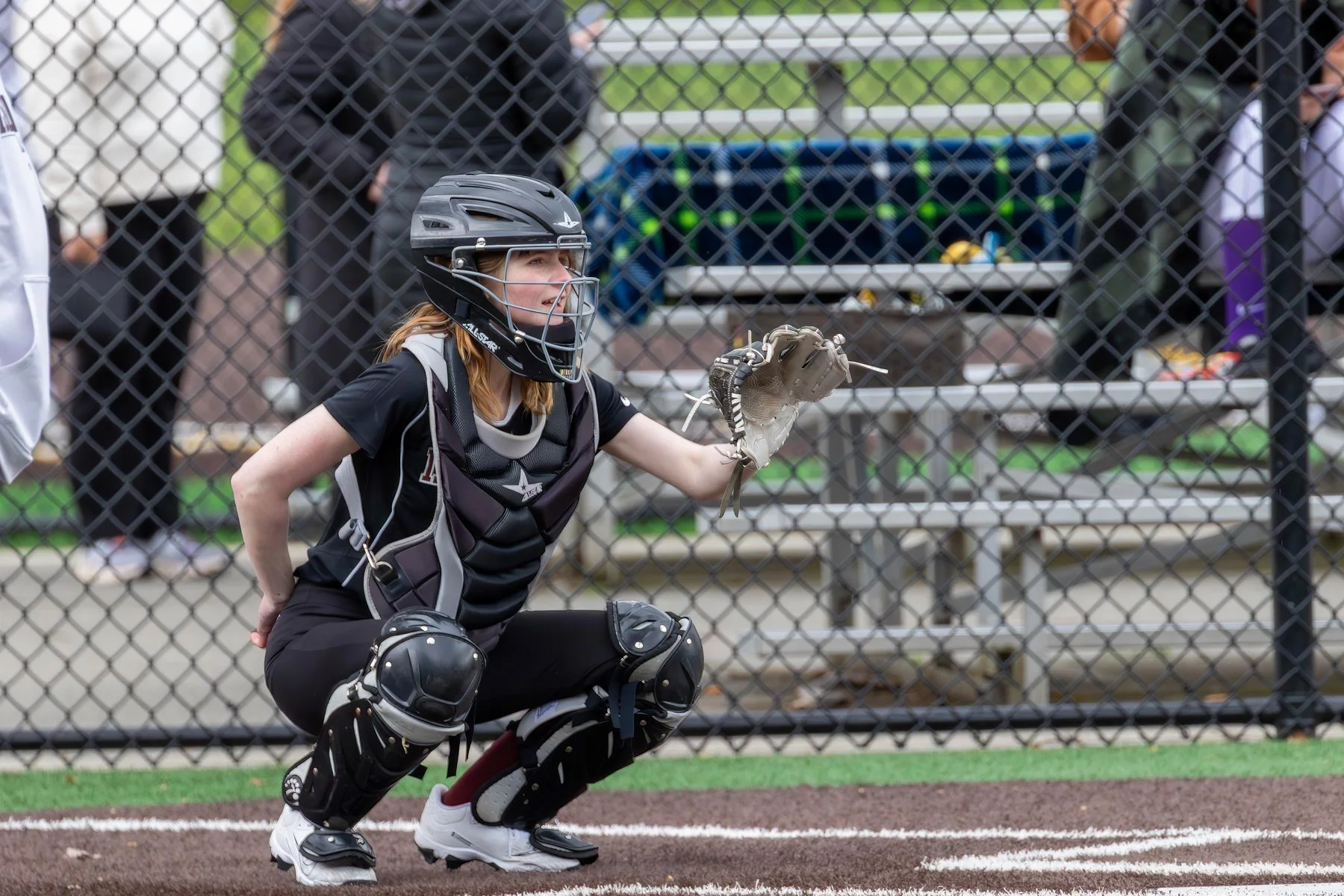 Islander softball catcher crouches with her glove raised.