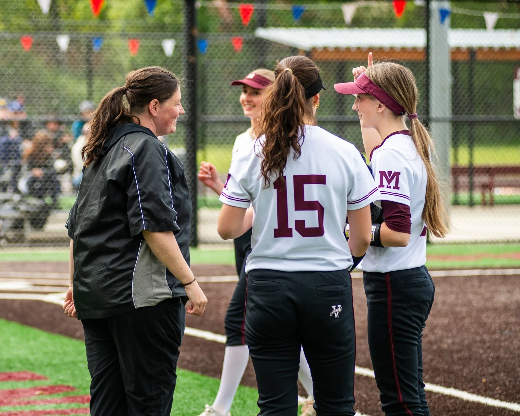 Coach talks with Mercer Island softball players on the infield.