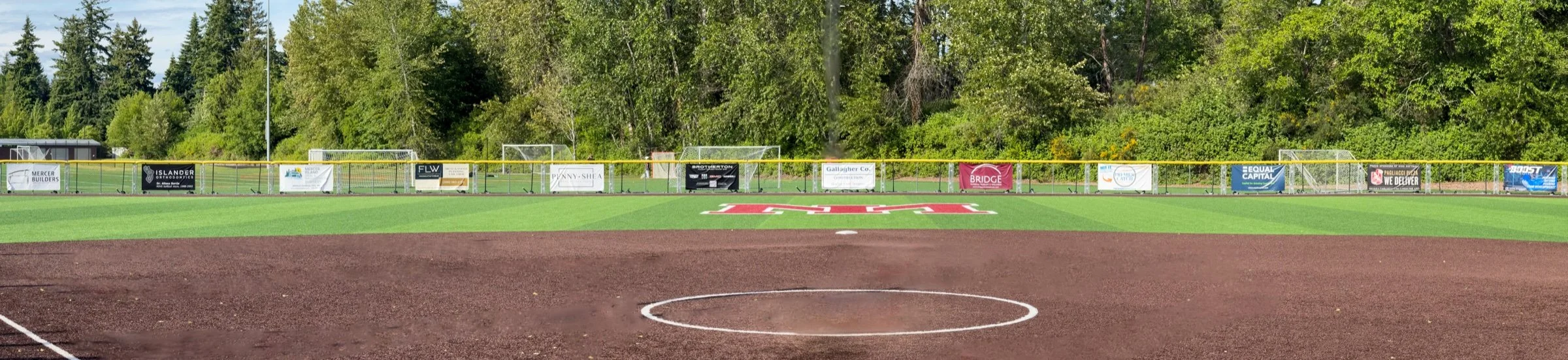 Sponsor banners lining the outfield fence at the Mercer Island softball field.