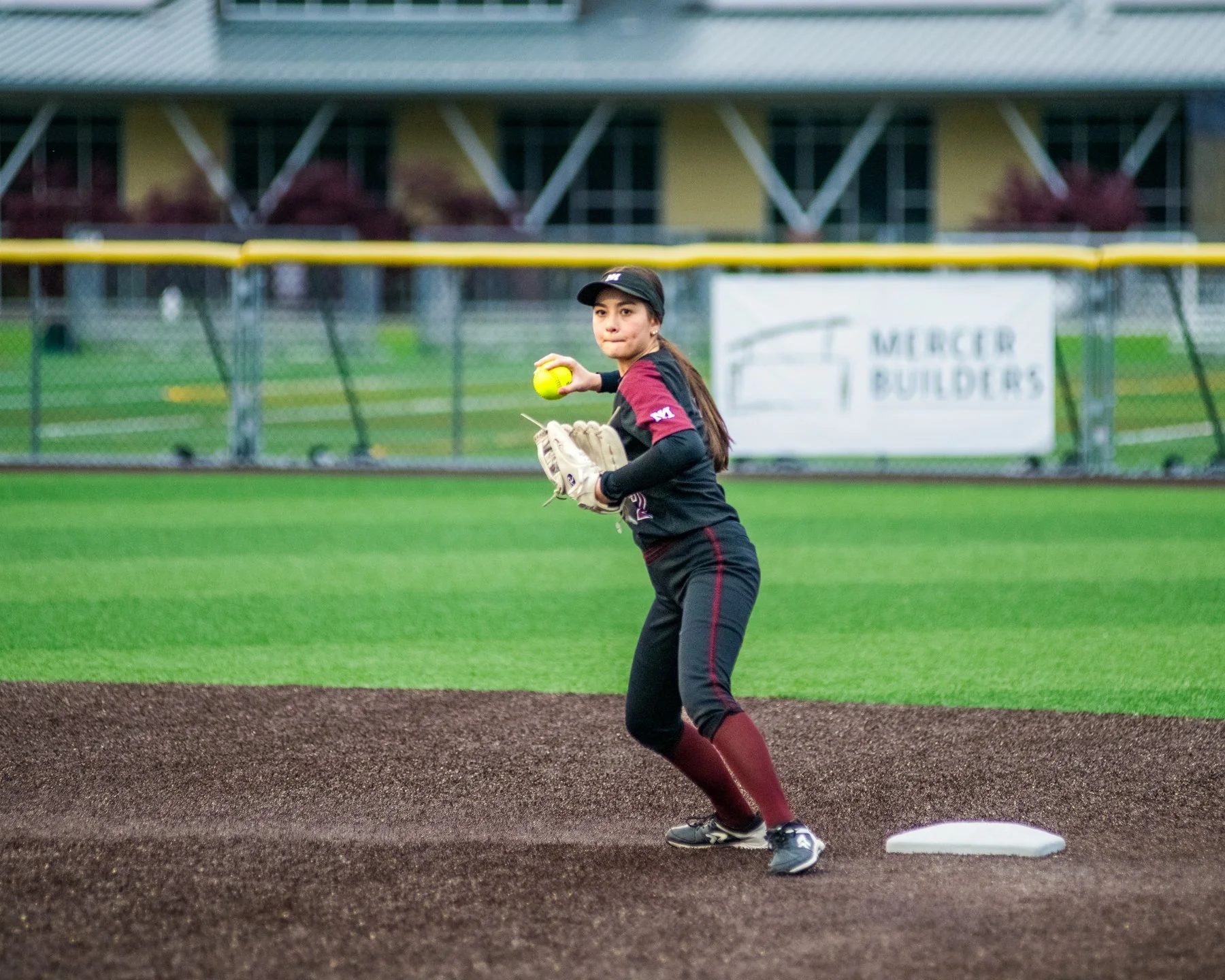 Islander softball player prepares a throw beside a base.